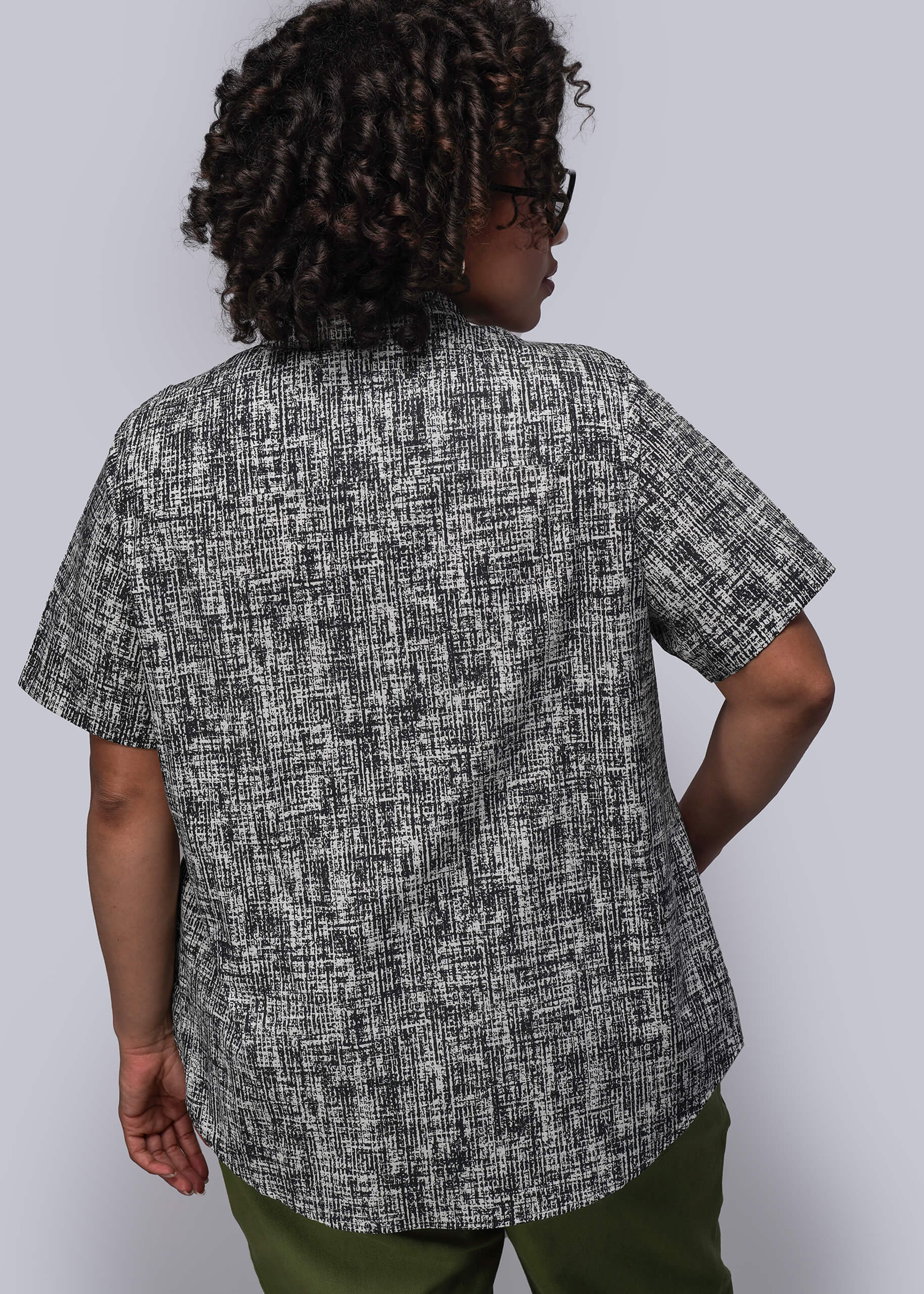 1X=Person wearing a black and white patterned shirt with green pants on a white background