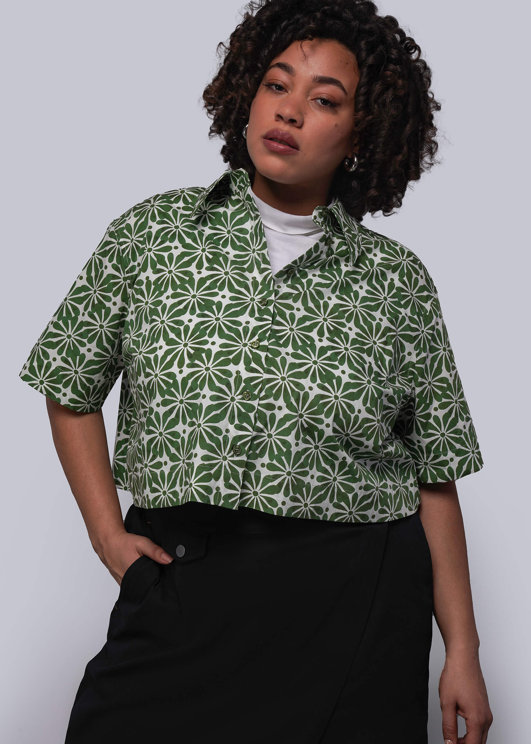 1X=Person wearing a green patterned shirt with a plain background