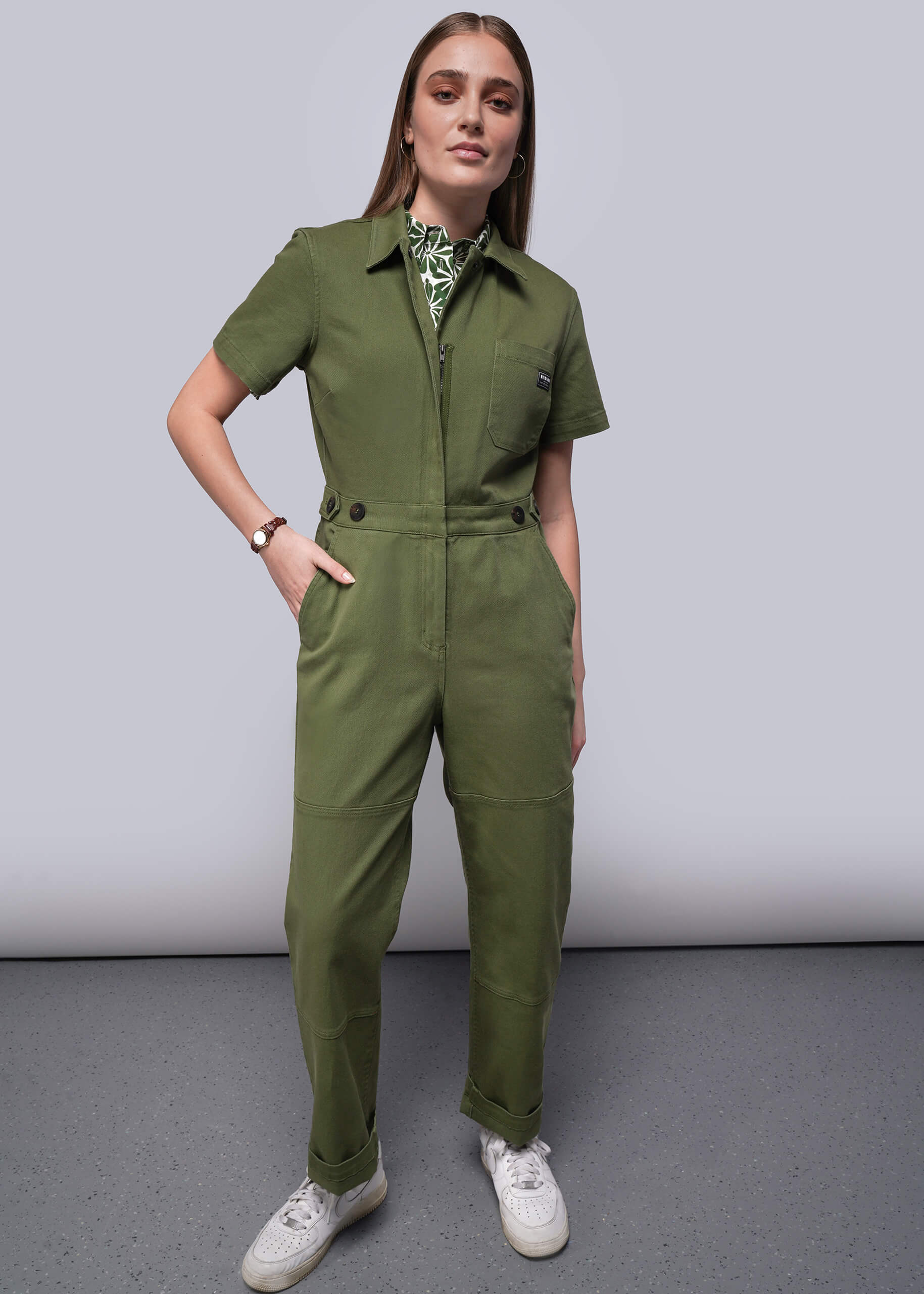 Woman wearing a green jumpsuit against a plain background