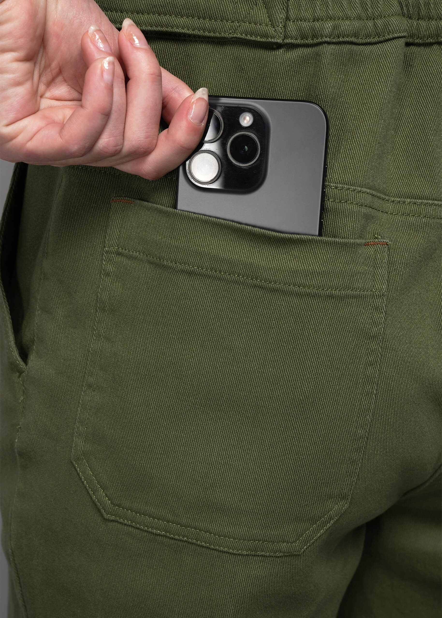 S=Person placing a phone in a green jumpsuit back pocket