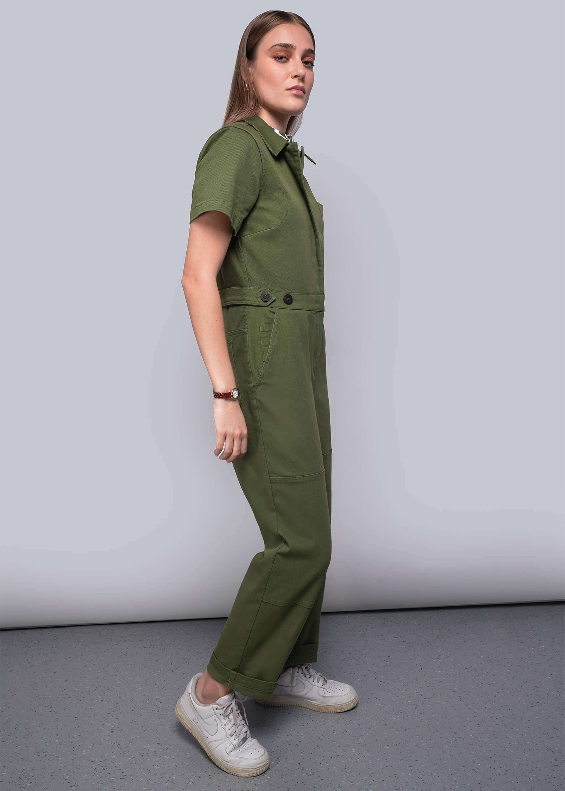 Woman wearing a green jumpsuit standing against a plain background