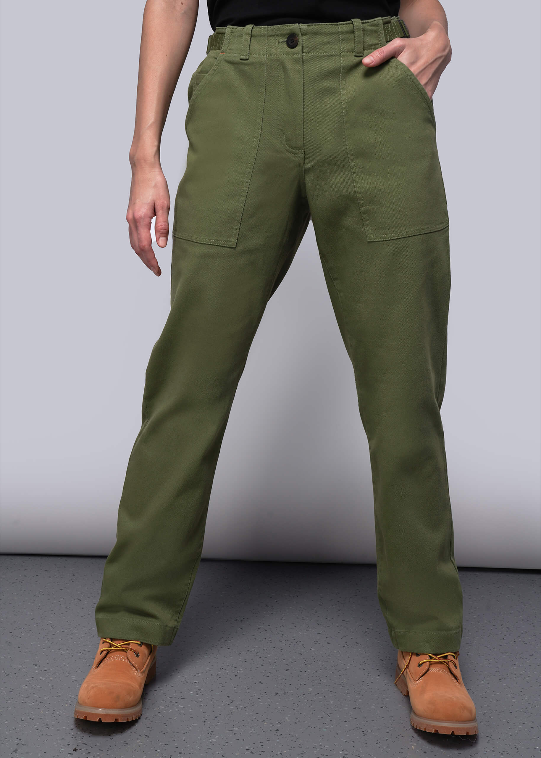 Person wearing green pants and brown boots on a gray background