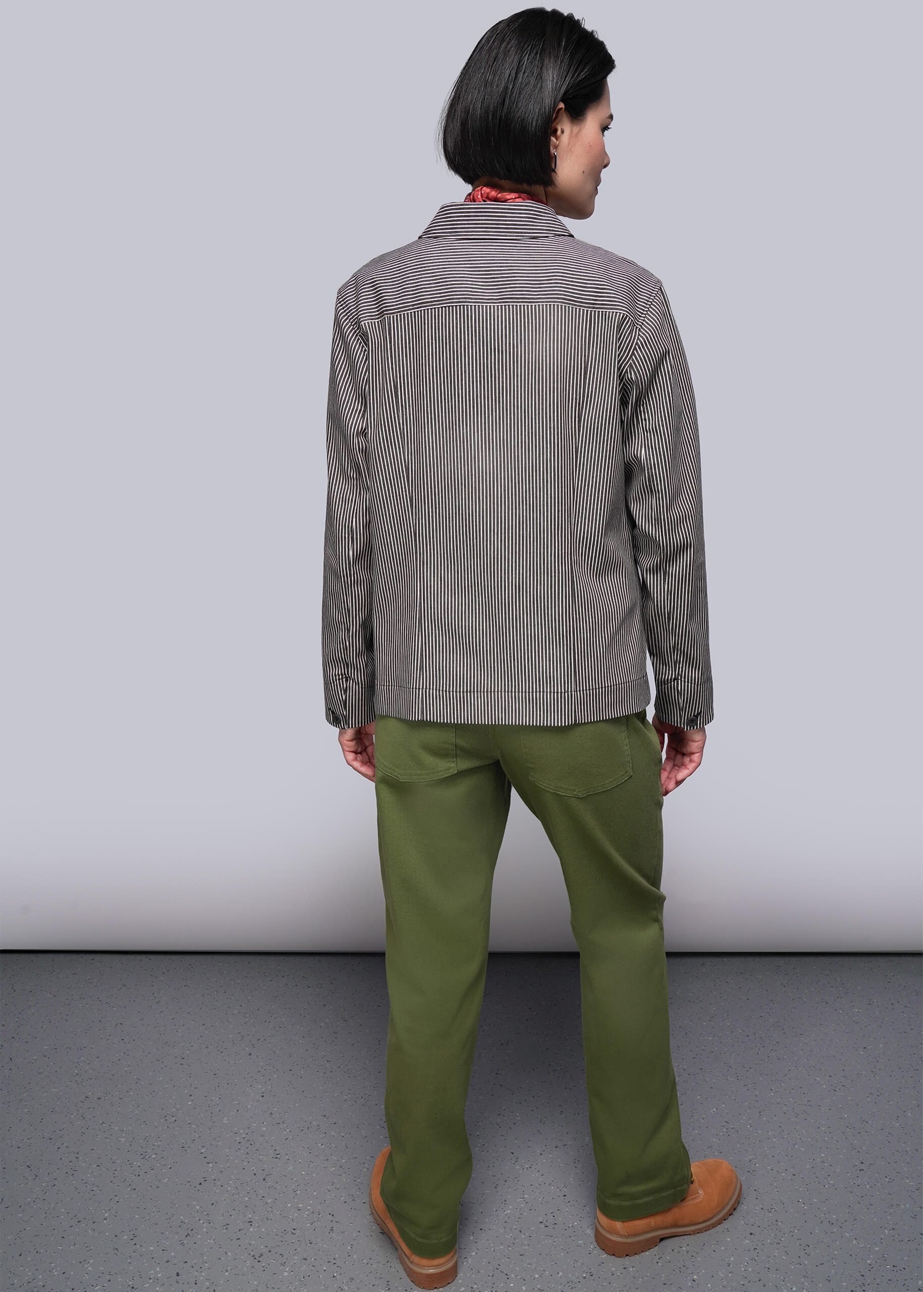 S=Person wearing a brown and white striped jacket and green pants against a plain background