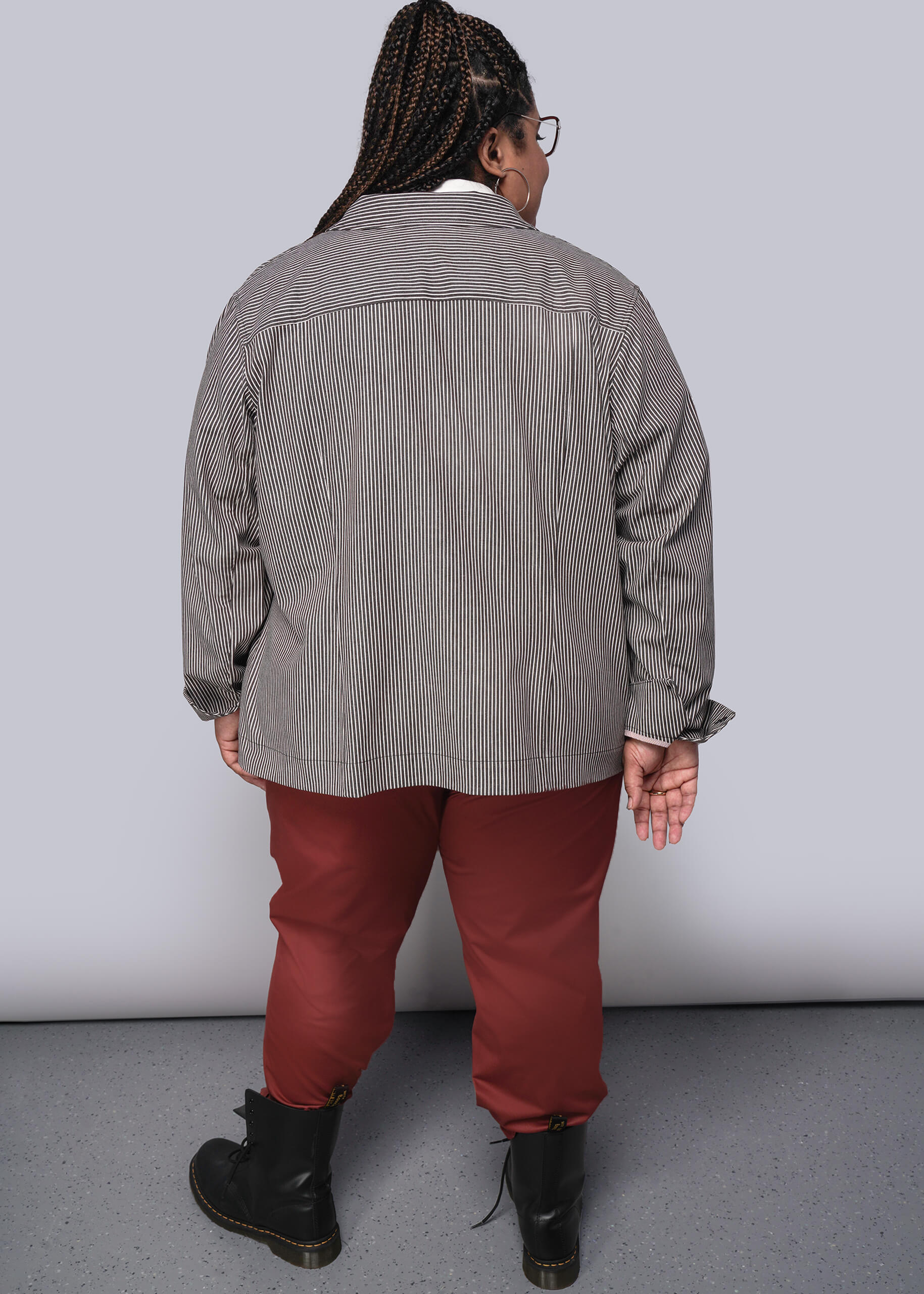 1X=Person wearing a brown and white striped striped jacket and red pants against a white background