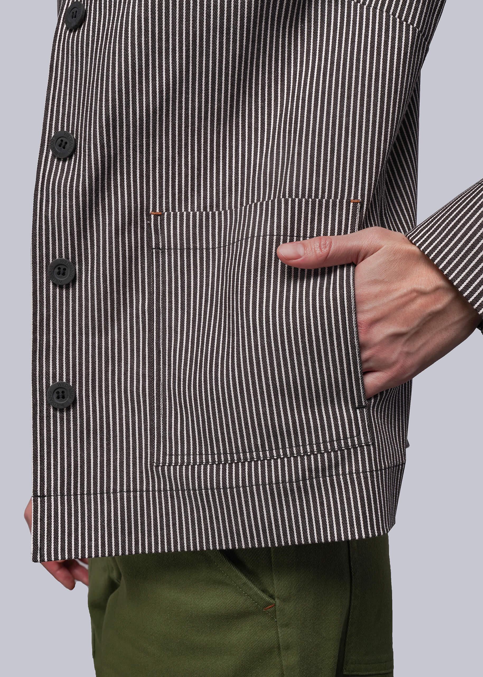 S=Person wearing a striped jacket with a pocket on a plain background