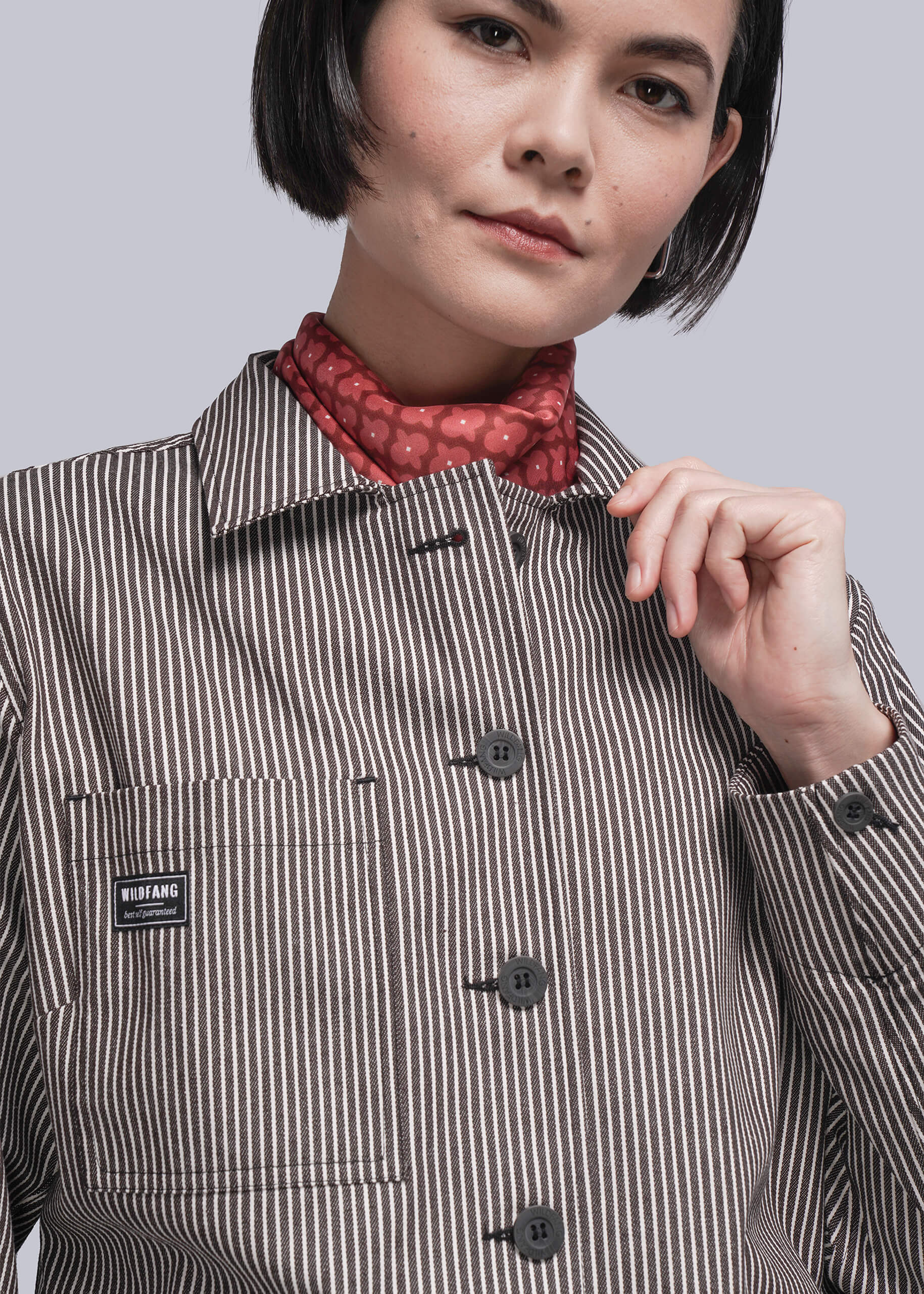 S=Person wearing a striped jacket with a brand label, holding the collar.