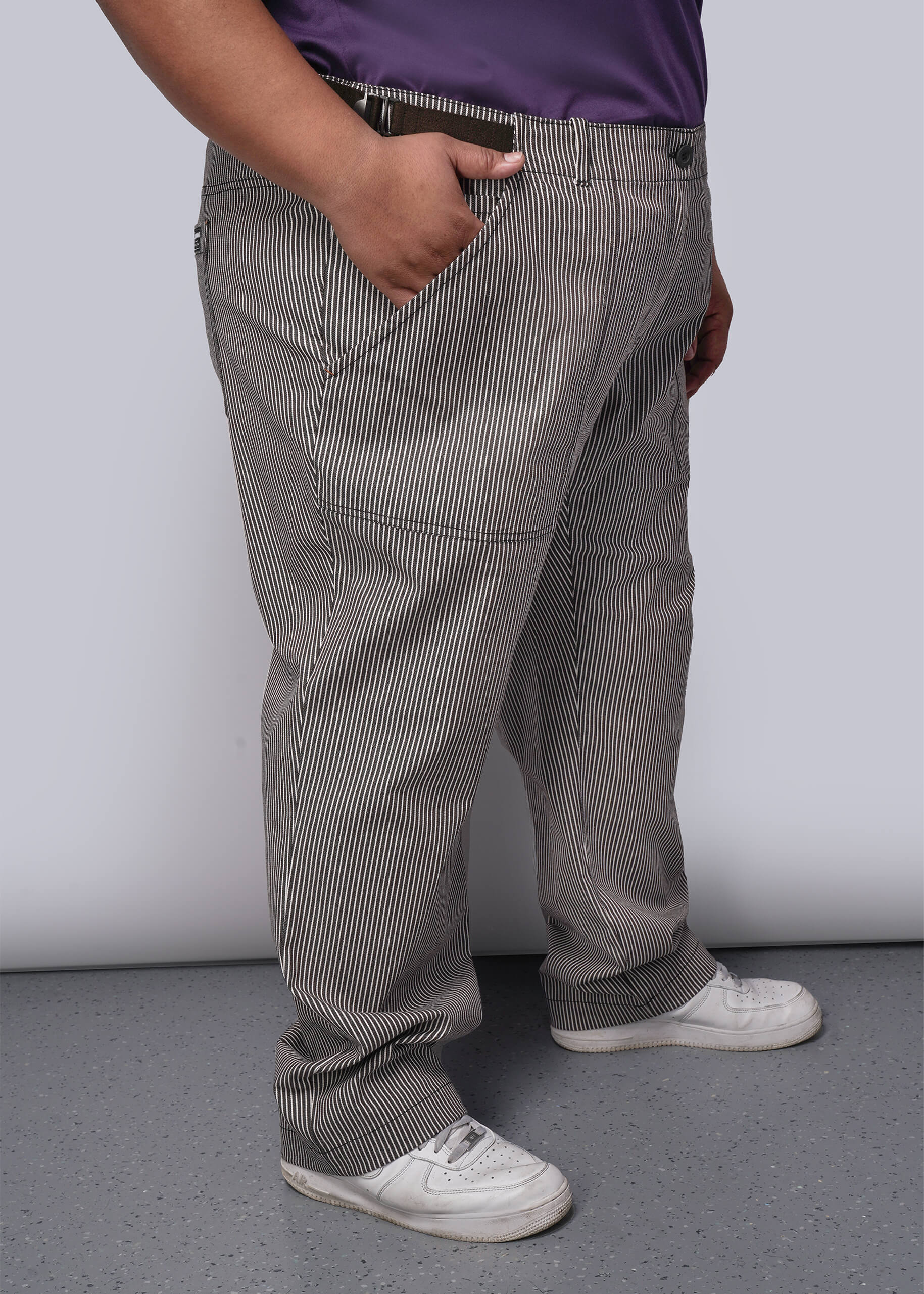 1X=Person wearing brown striped pants and white sneakers against a plain background