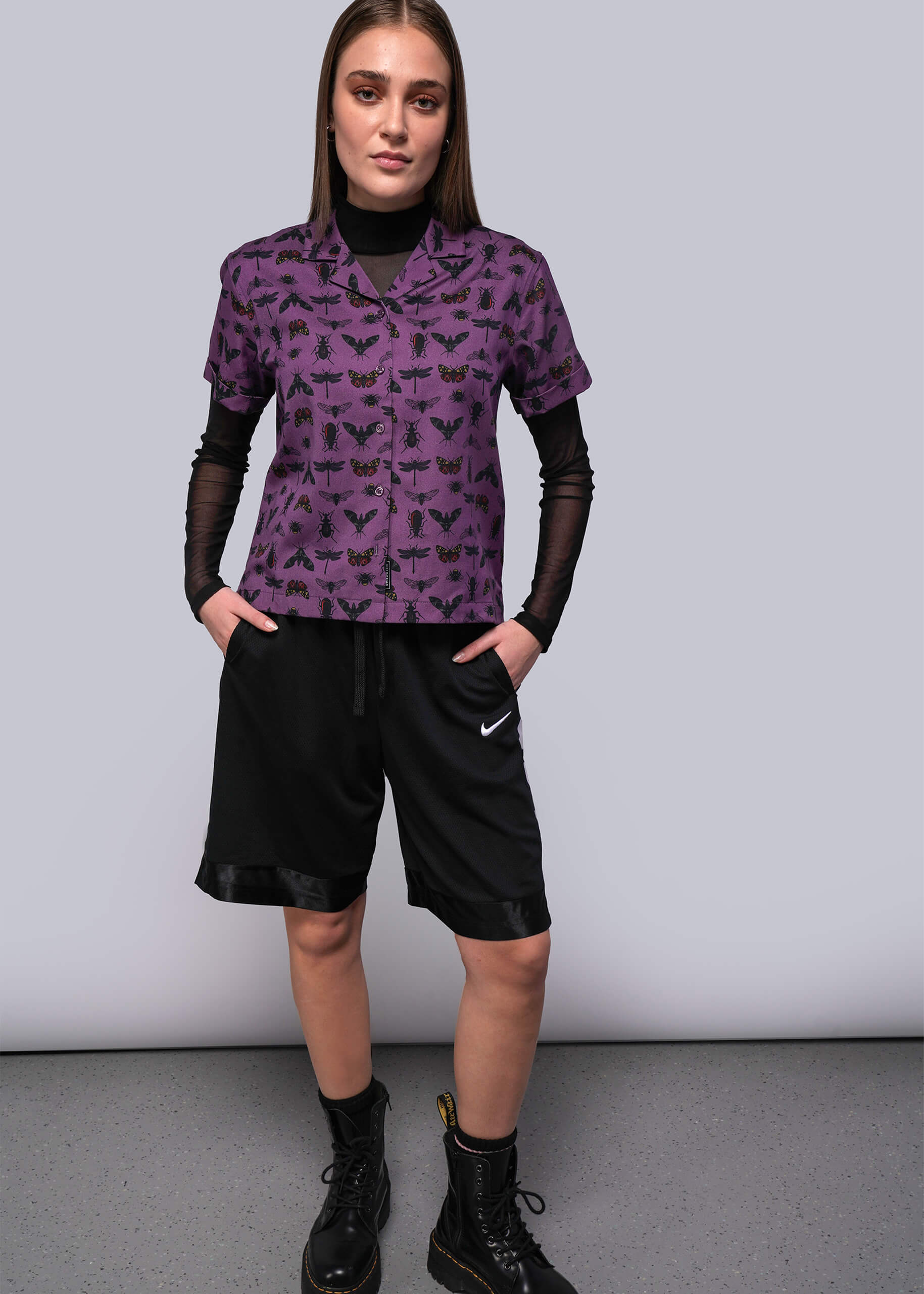 Person wearing a purple patterned shirt and black shorts with a Nike logo.