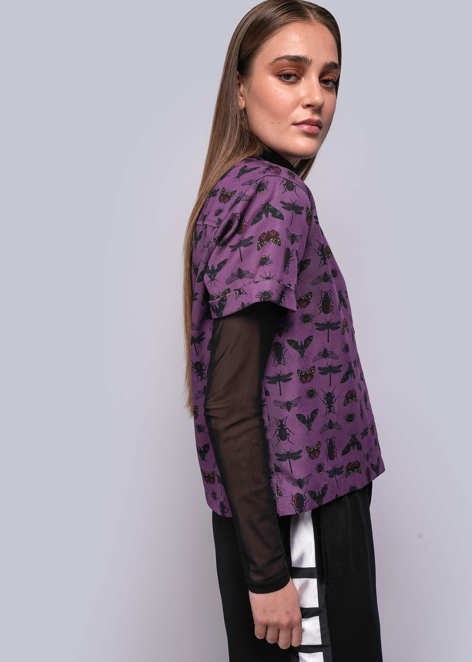 S=Woman wearing a purple patterned jacket on a plain background