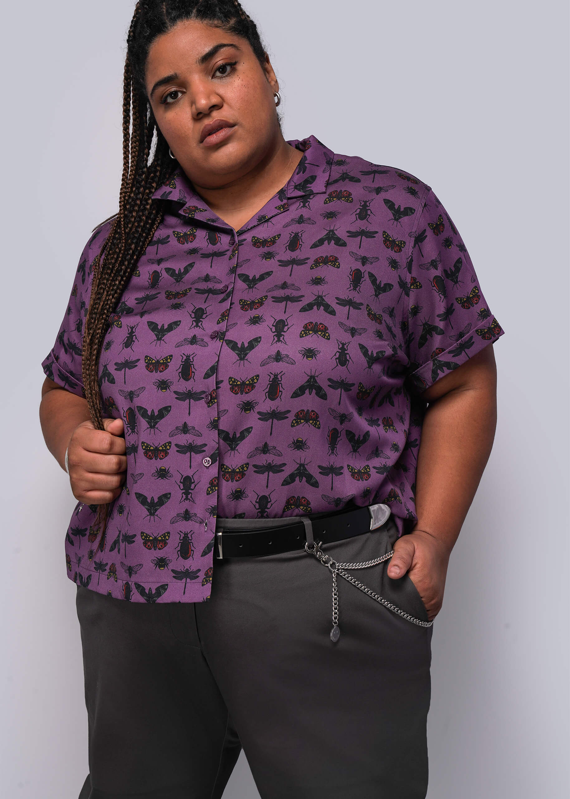 1X=Person wearing a purple patterned shirt and gray pants against a white background