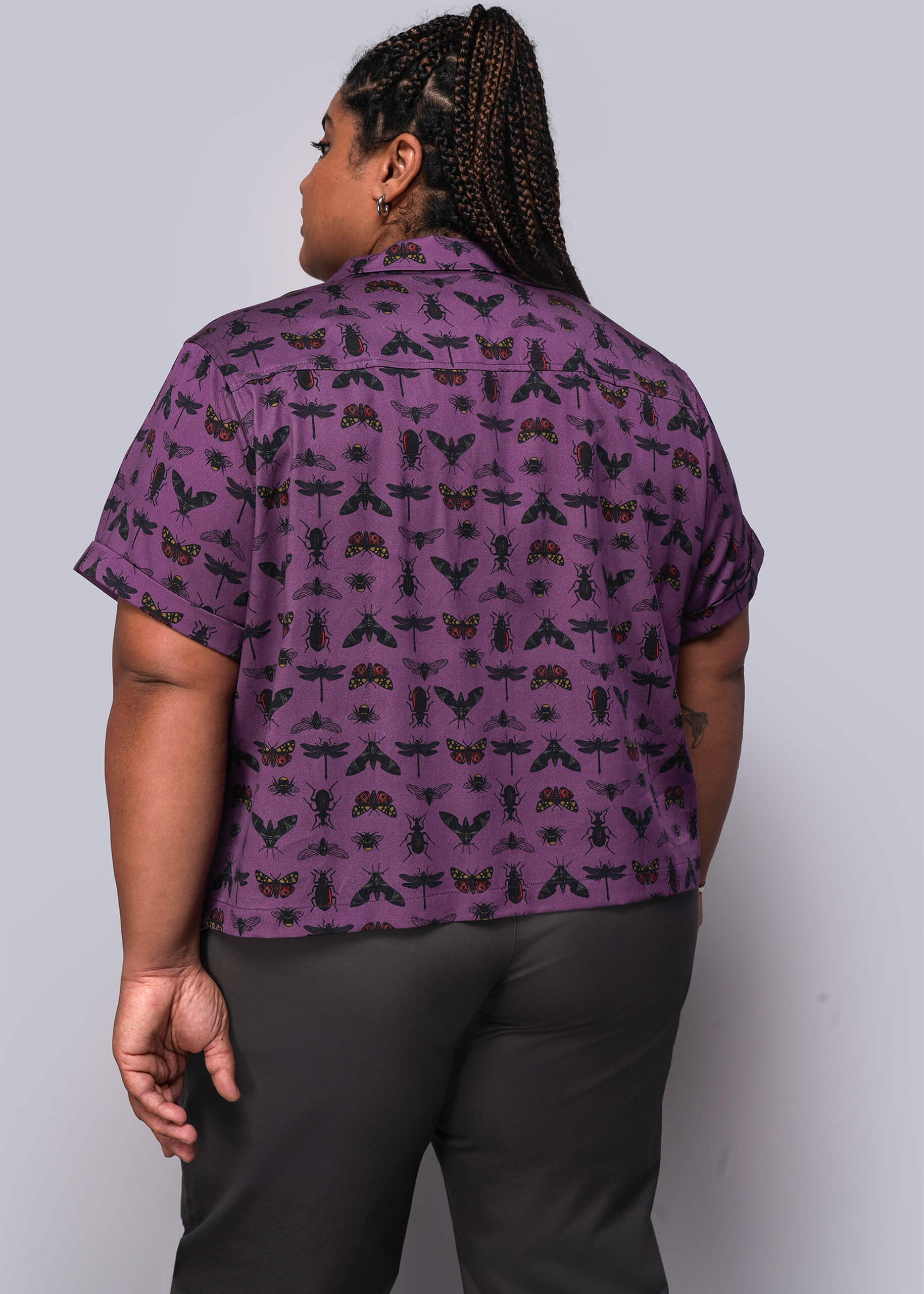 1X=Person wearing a purple patterned shirt against a plain background