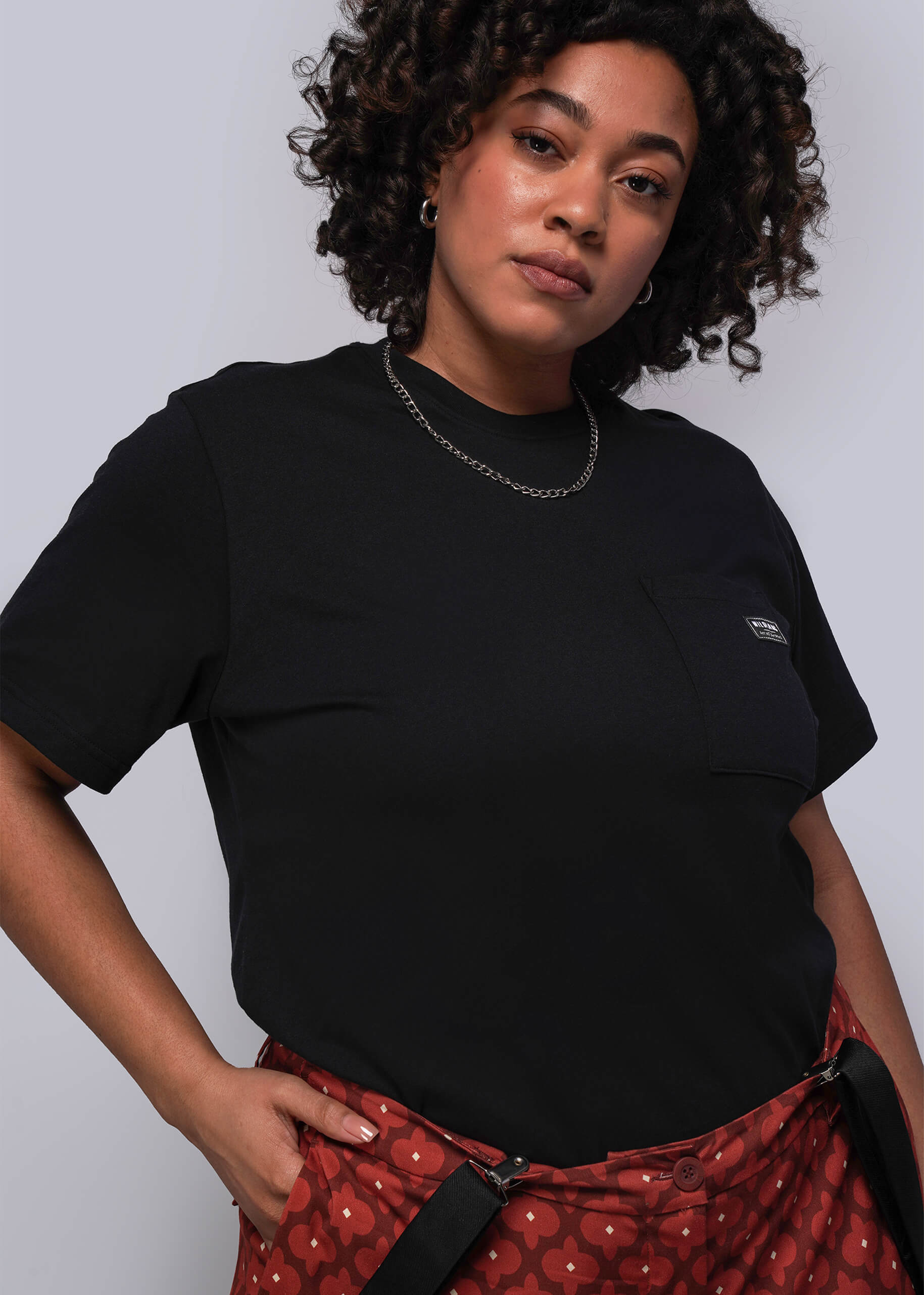 1X=Person wearing a black t-shirt with a small logo on a plain background