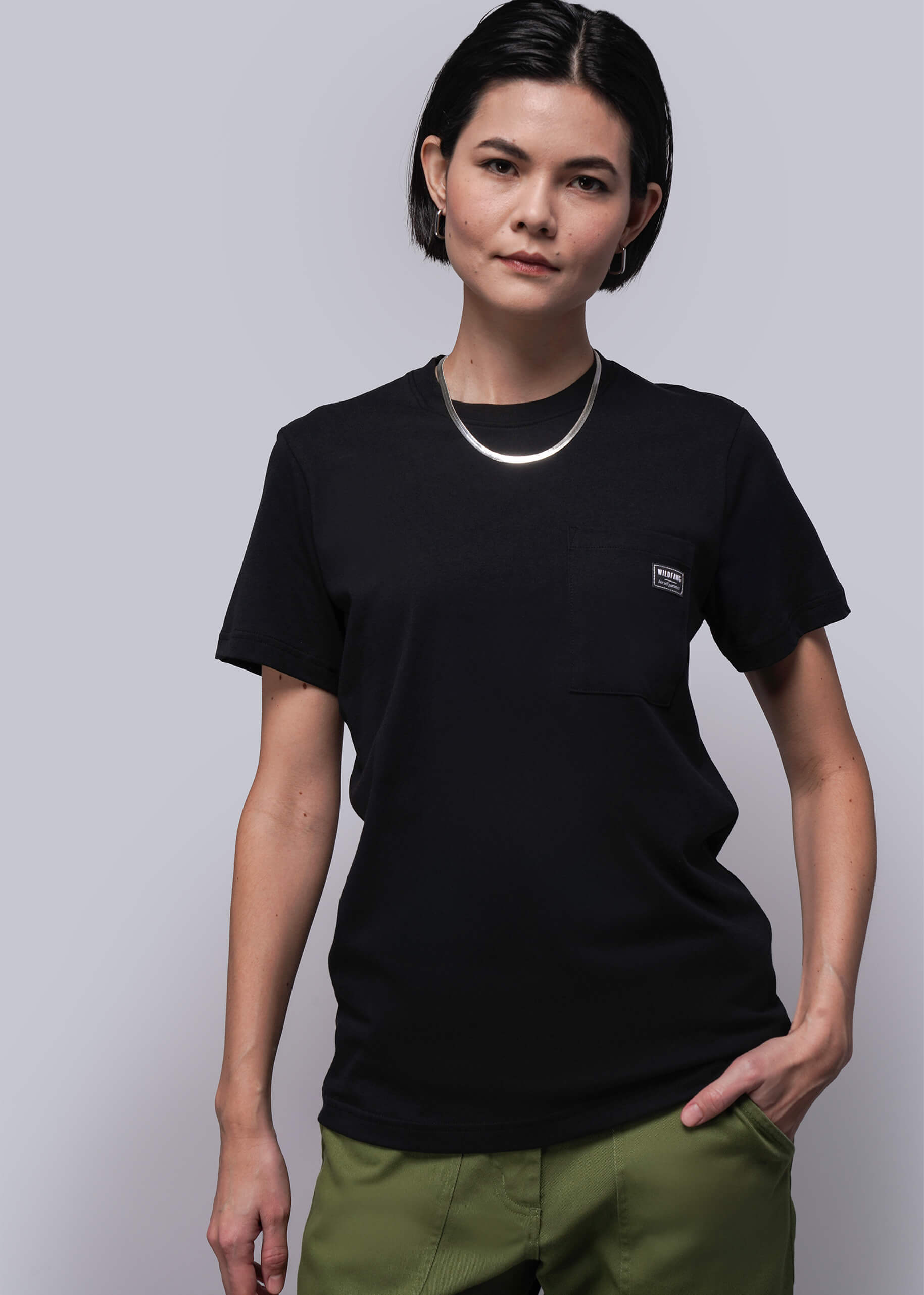 S=Person wearing a black t-shirt with a small logo on a plain background