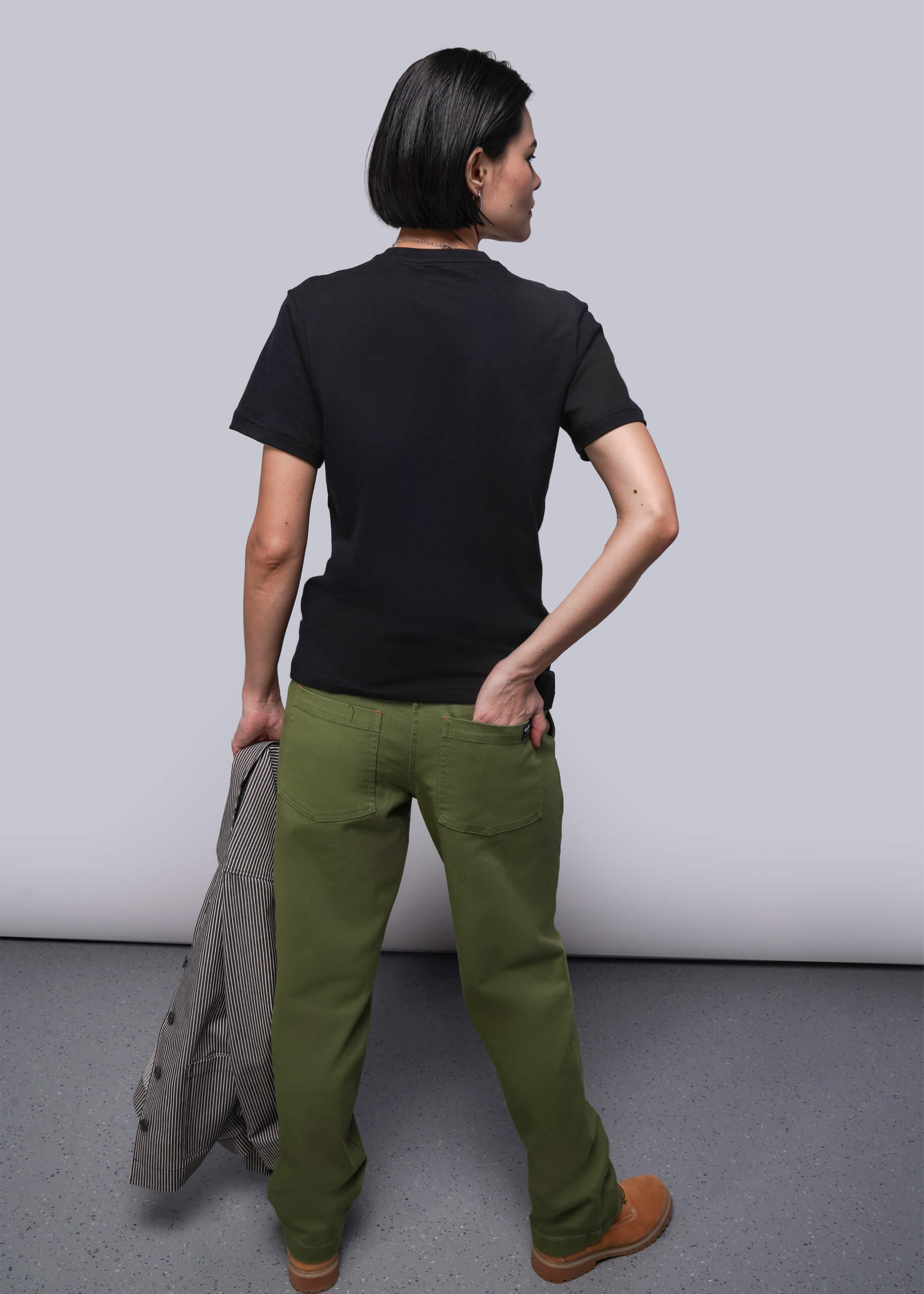 S=Person wearing a black t-shirt and green pants against a plain background