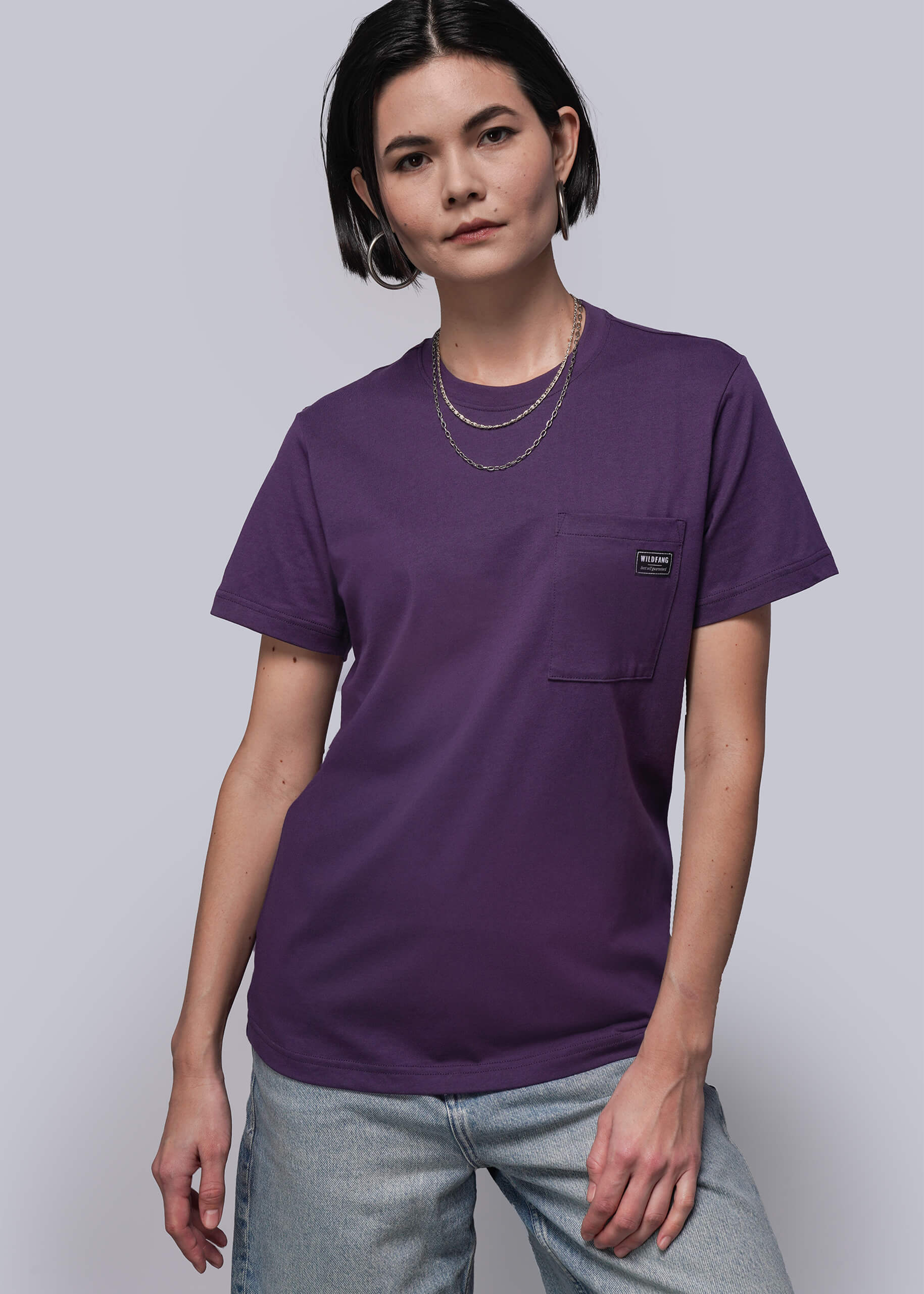 S=Person wearing a purple t-shirt with a pocket on a plain background