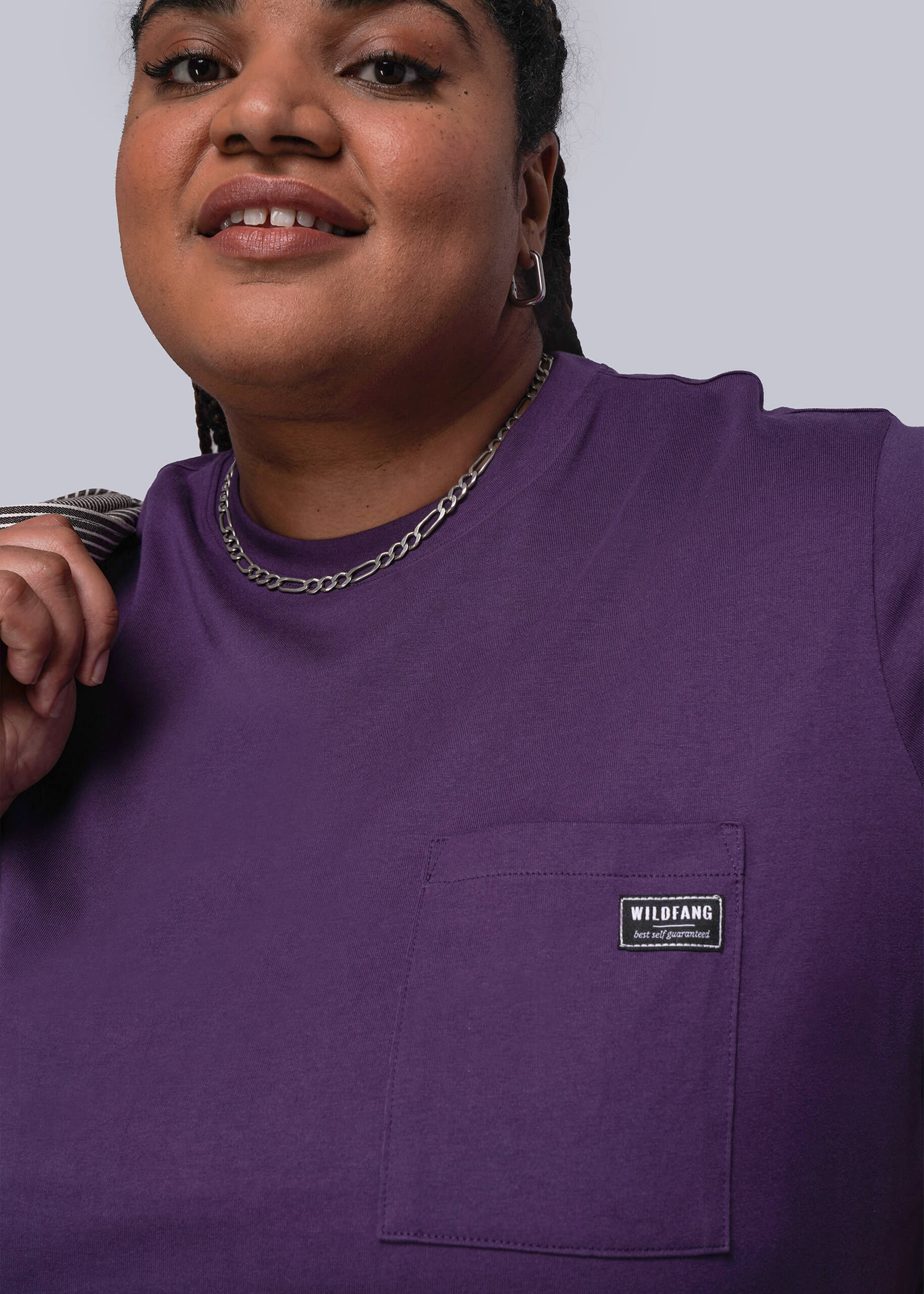 1X=Person wearing a purple shirt with a visible brand logo on a plain background
