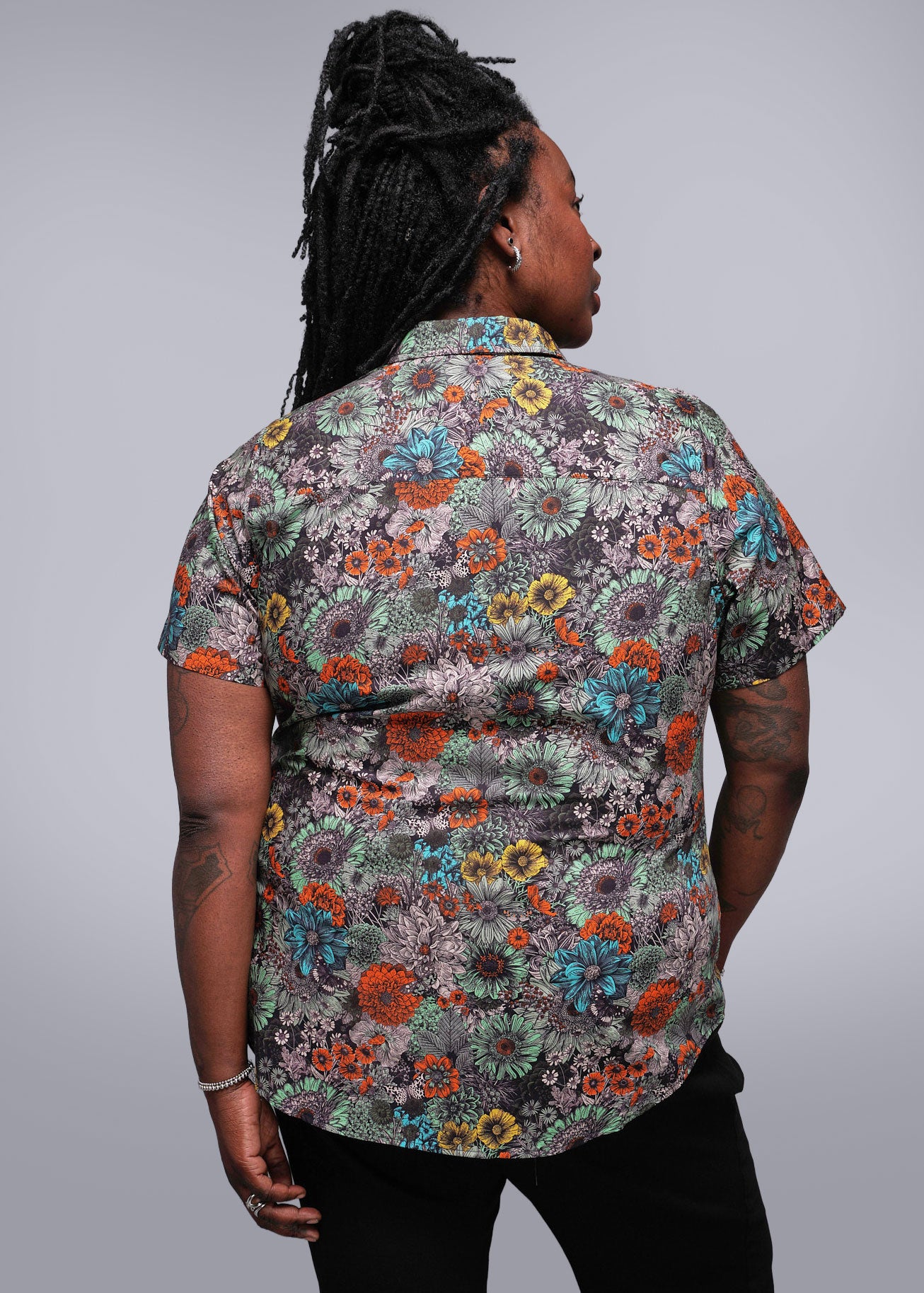 1X=Person wearing a colorful floral patterned shirt against a plain background