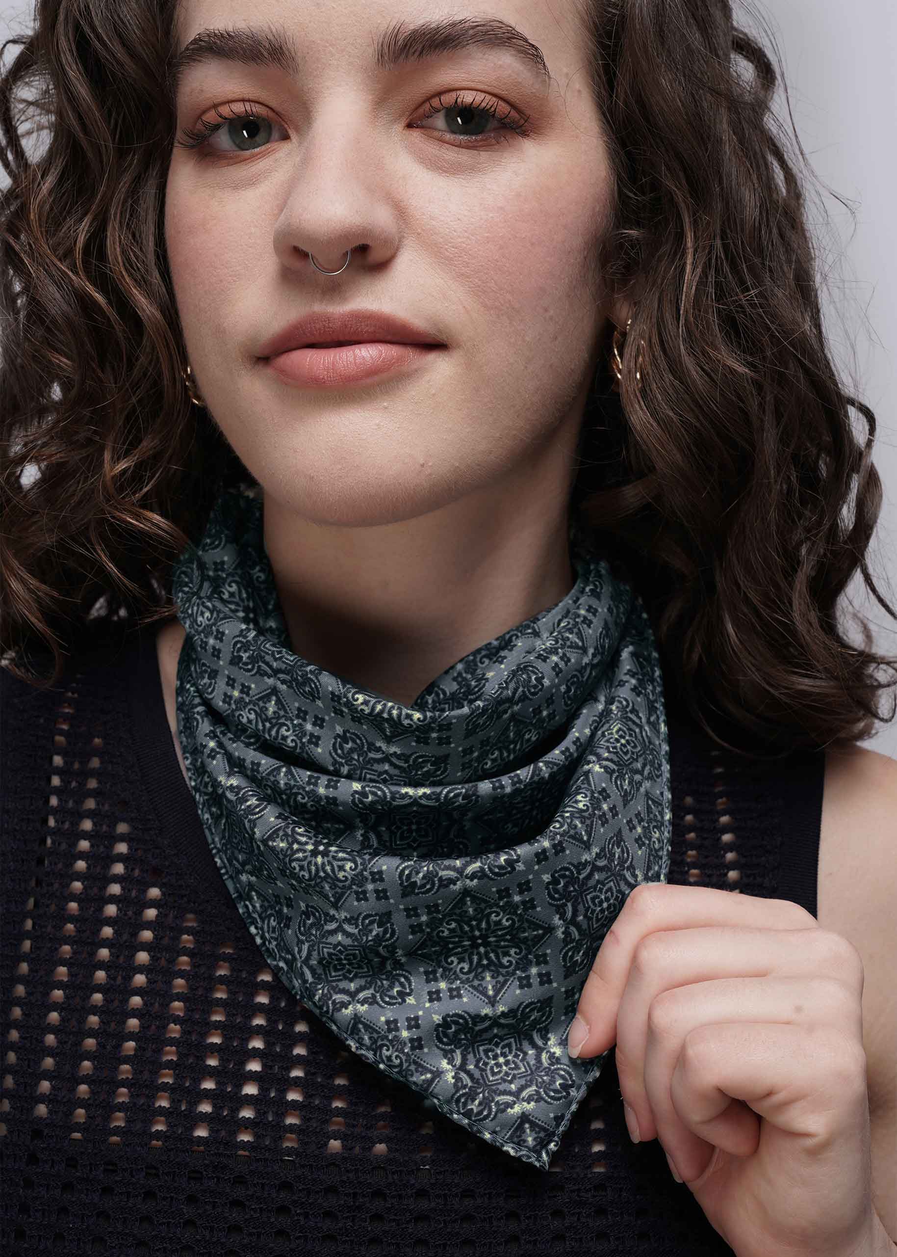 Woman wearing a teal patterned scarf against a neutral background