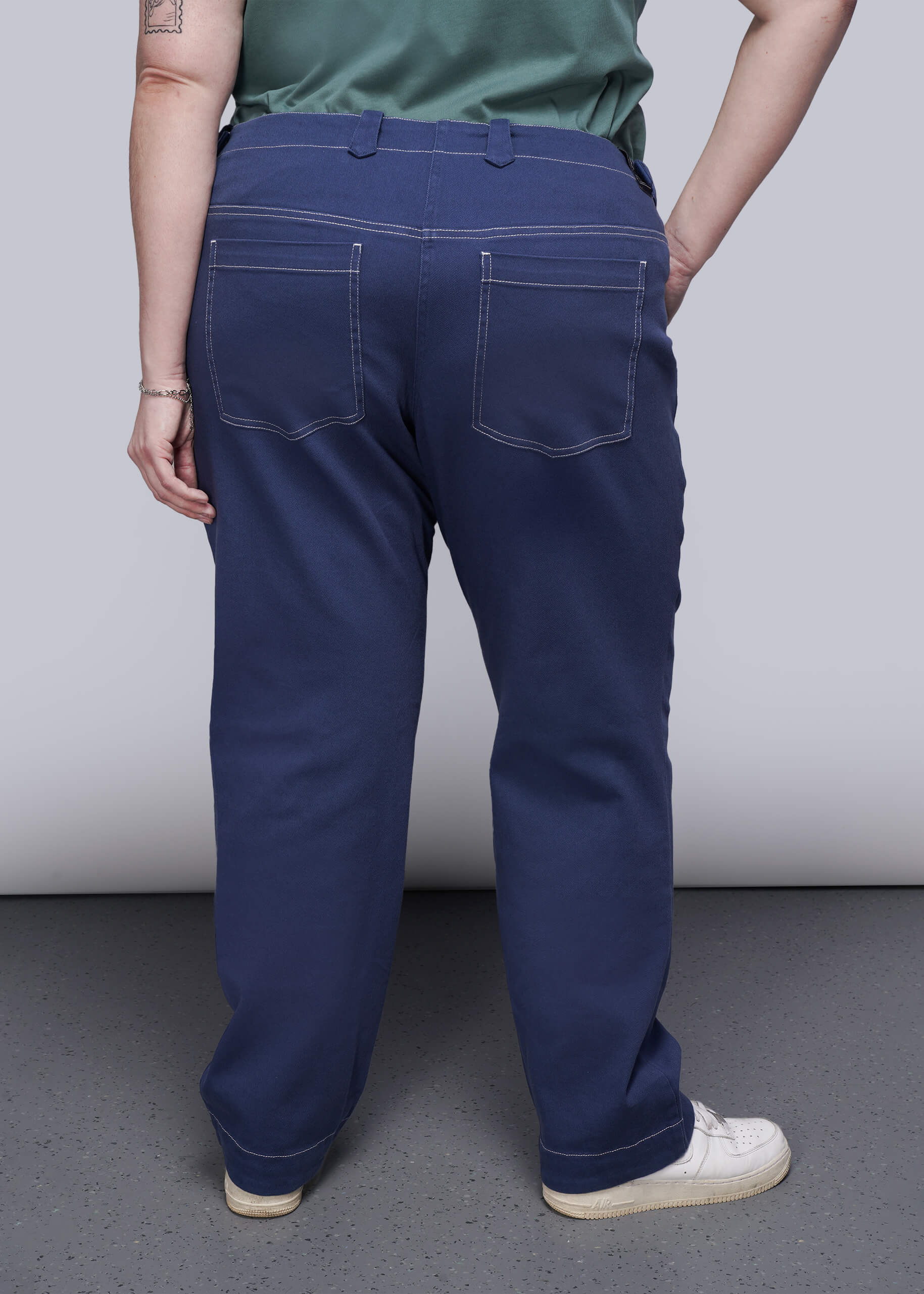 1X= Back of person wearing blue denim pants with a plain background