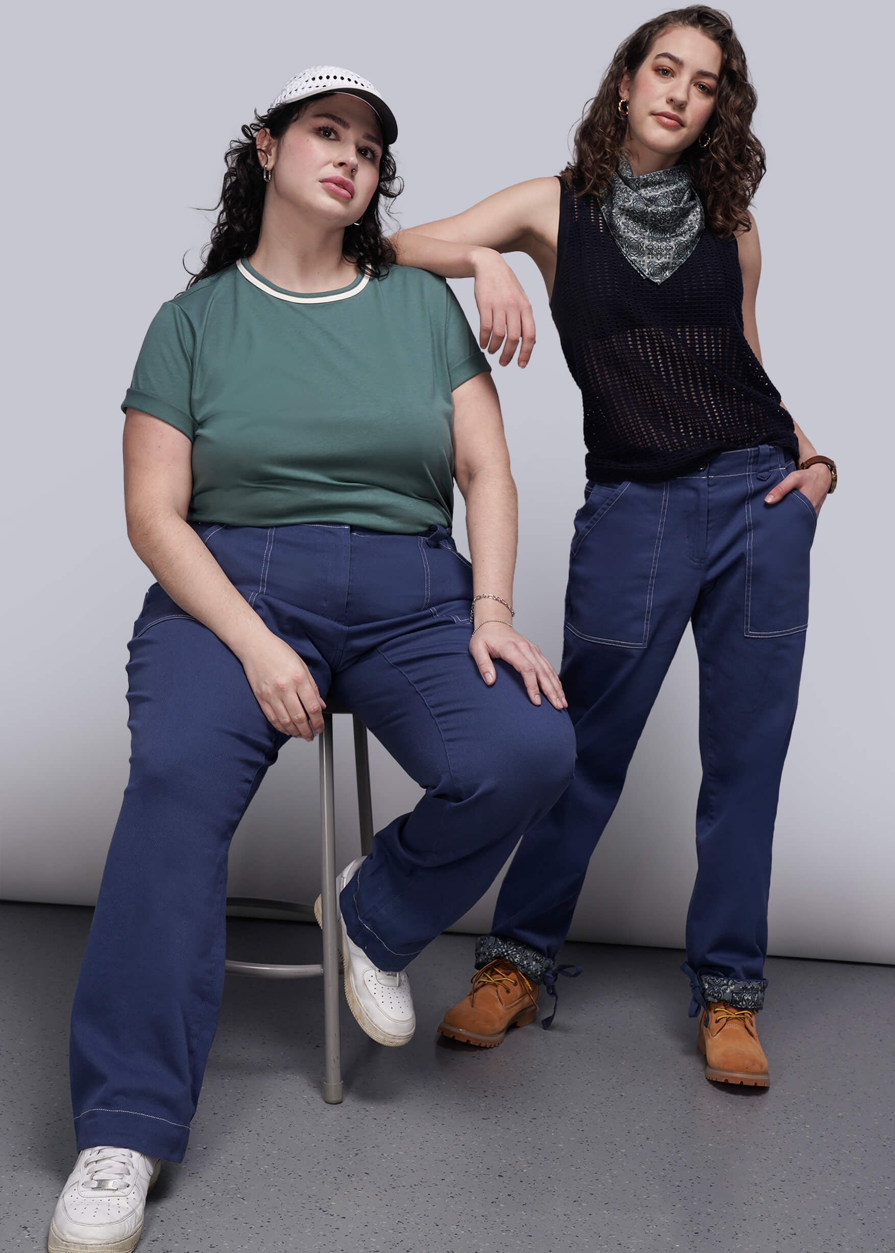 Two people wearing blue denim pants against a plain background