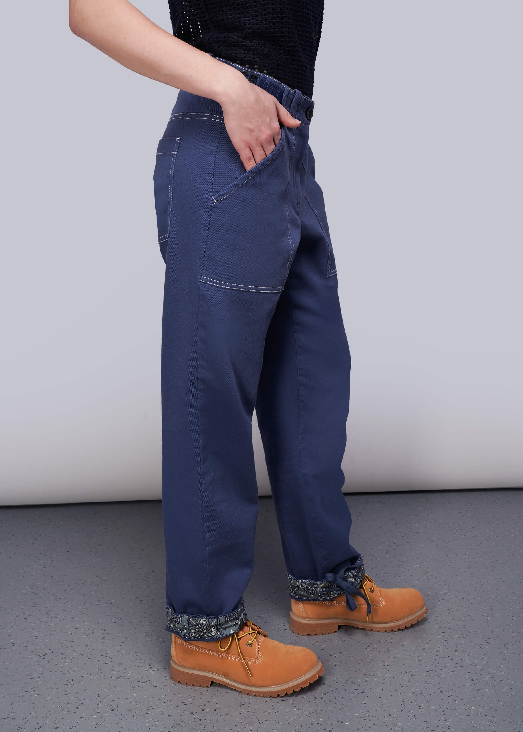S=Person wearing blue denim pants and brown boots on a plain background