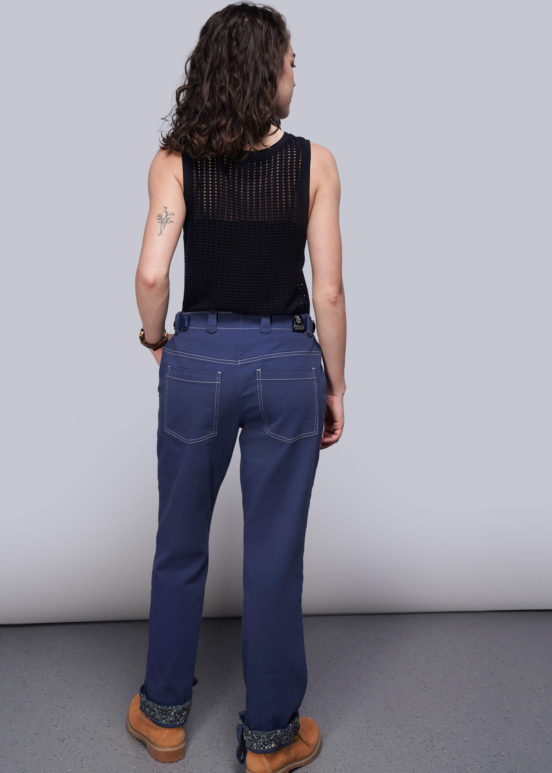 S=Person wearing blue denim pants and a navy blue knit mesh top on a plain background