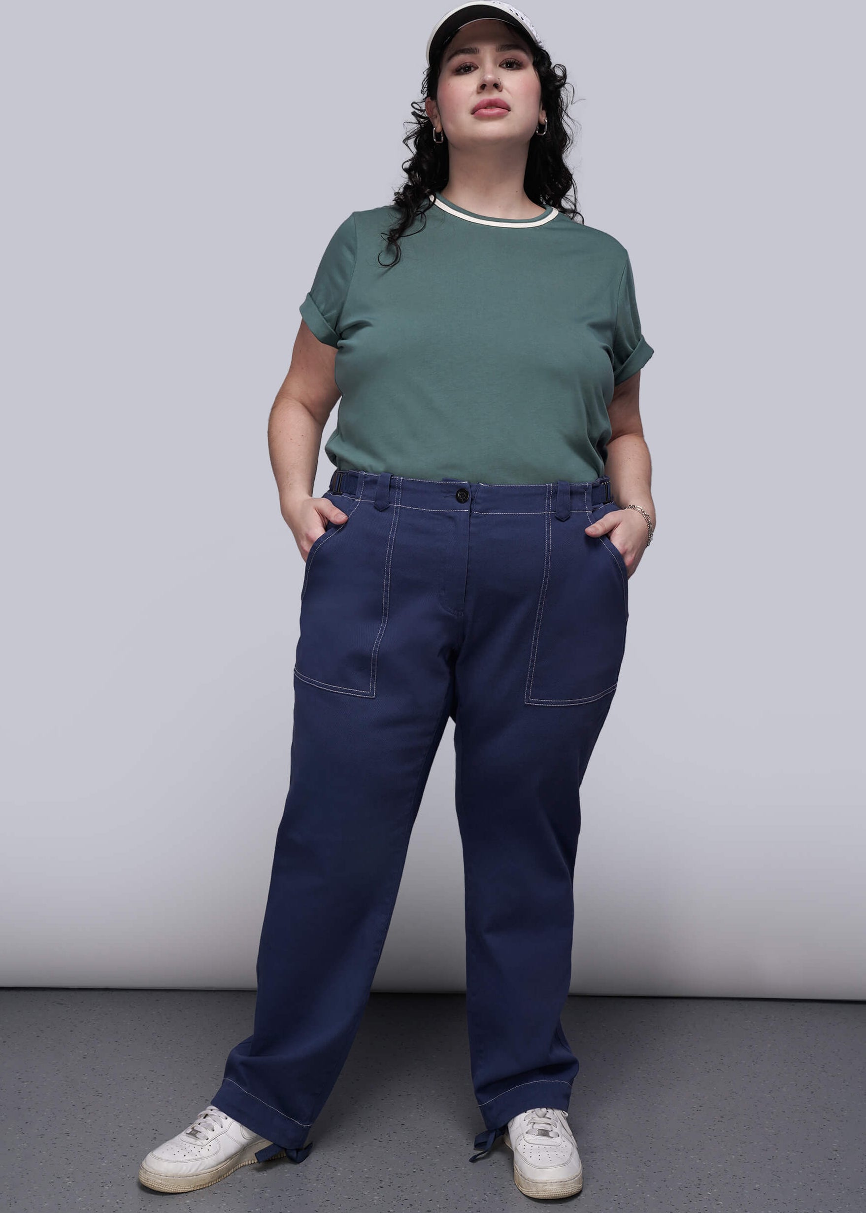 1X=Person wearing a teal t-shirt and blue denim pants against a plain background