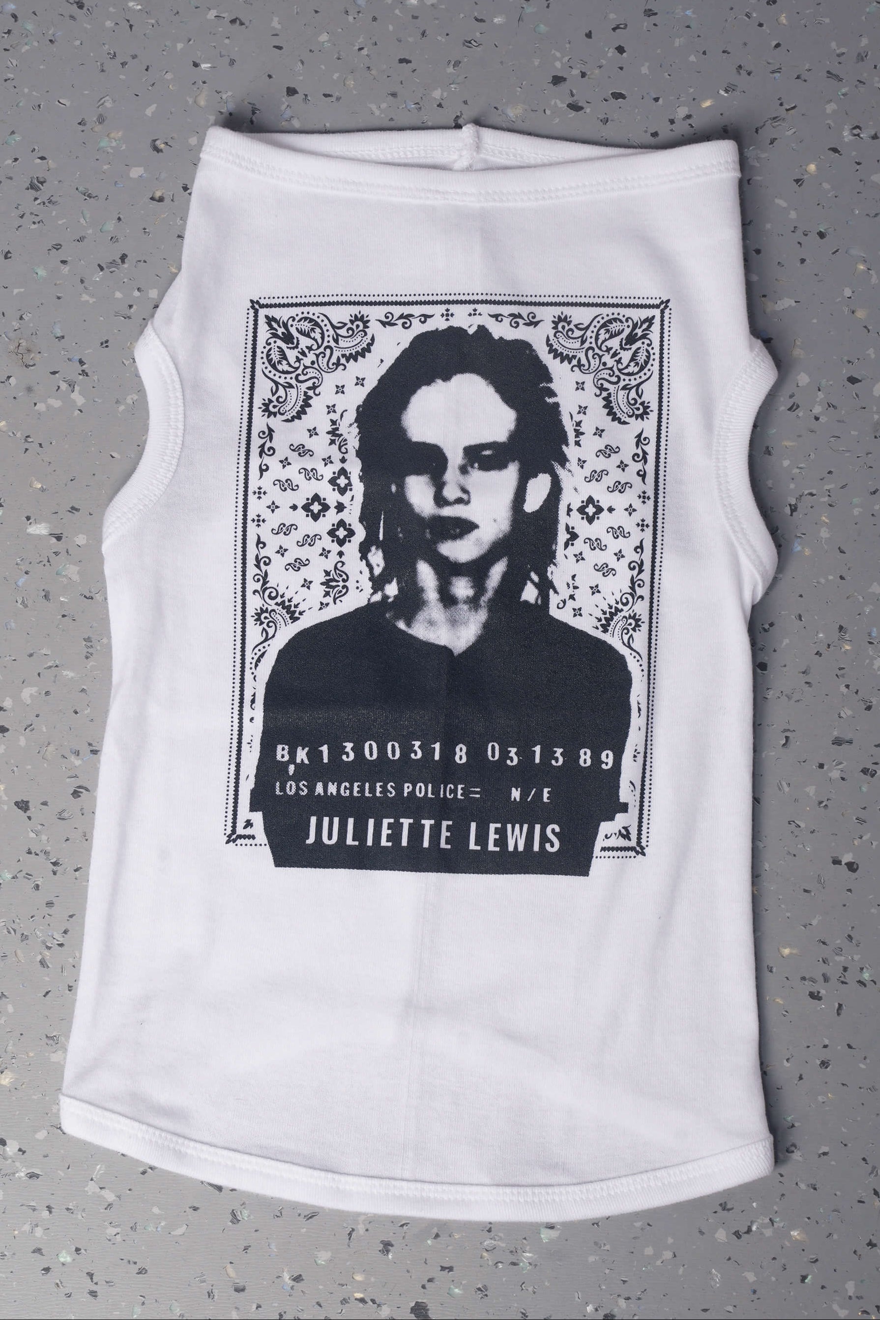White dog shirt with graphic design laying flat on a gray surface