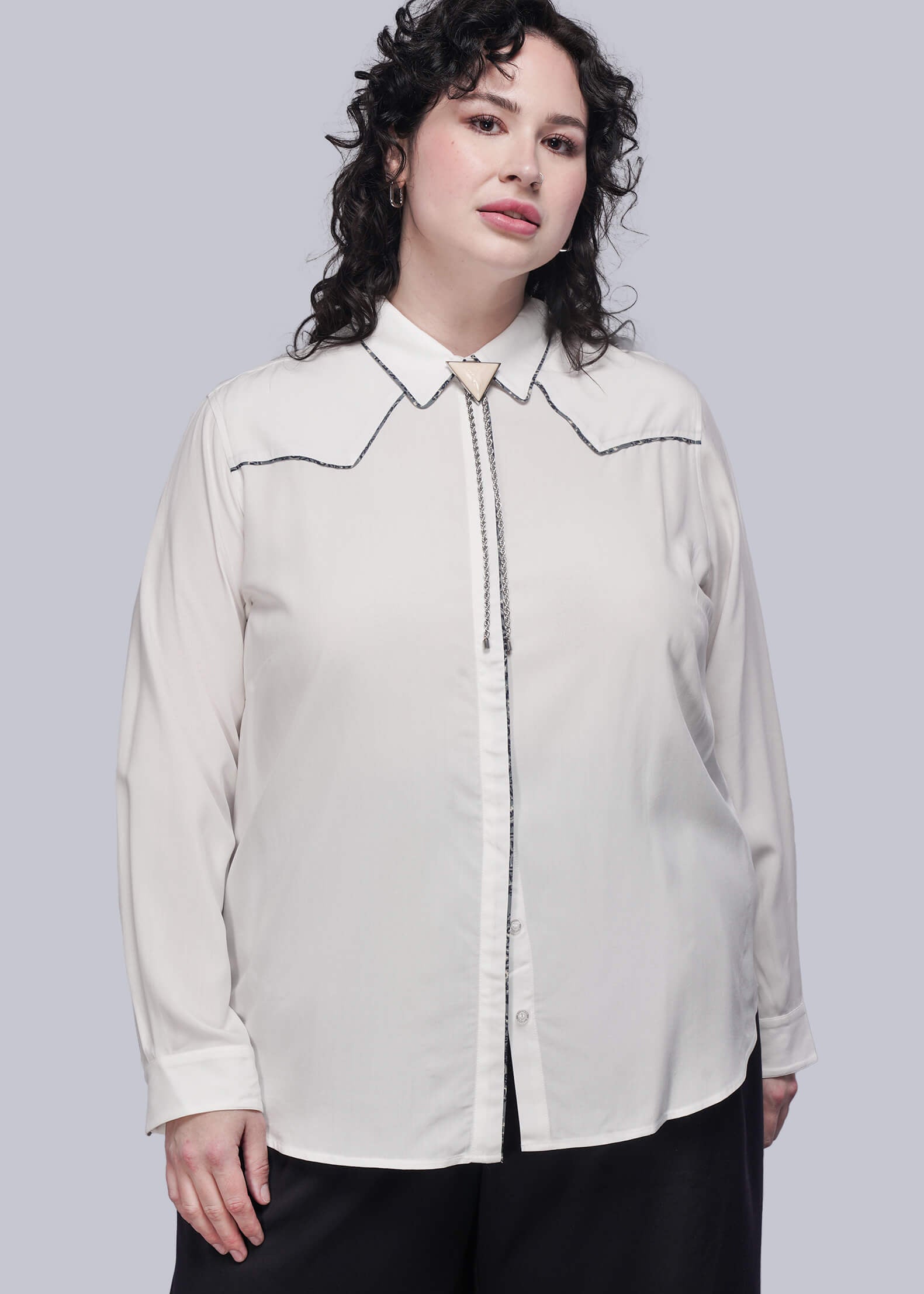 1X=Person wearing a white blouse with decorative trim on a gray background