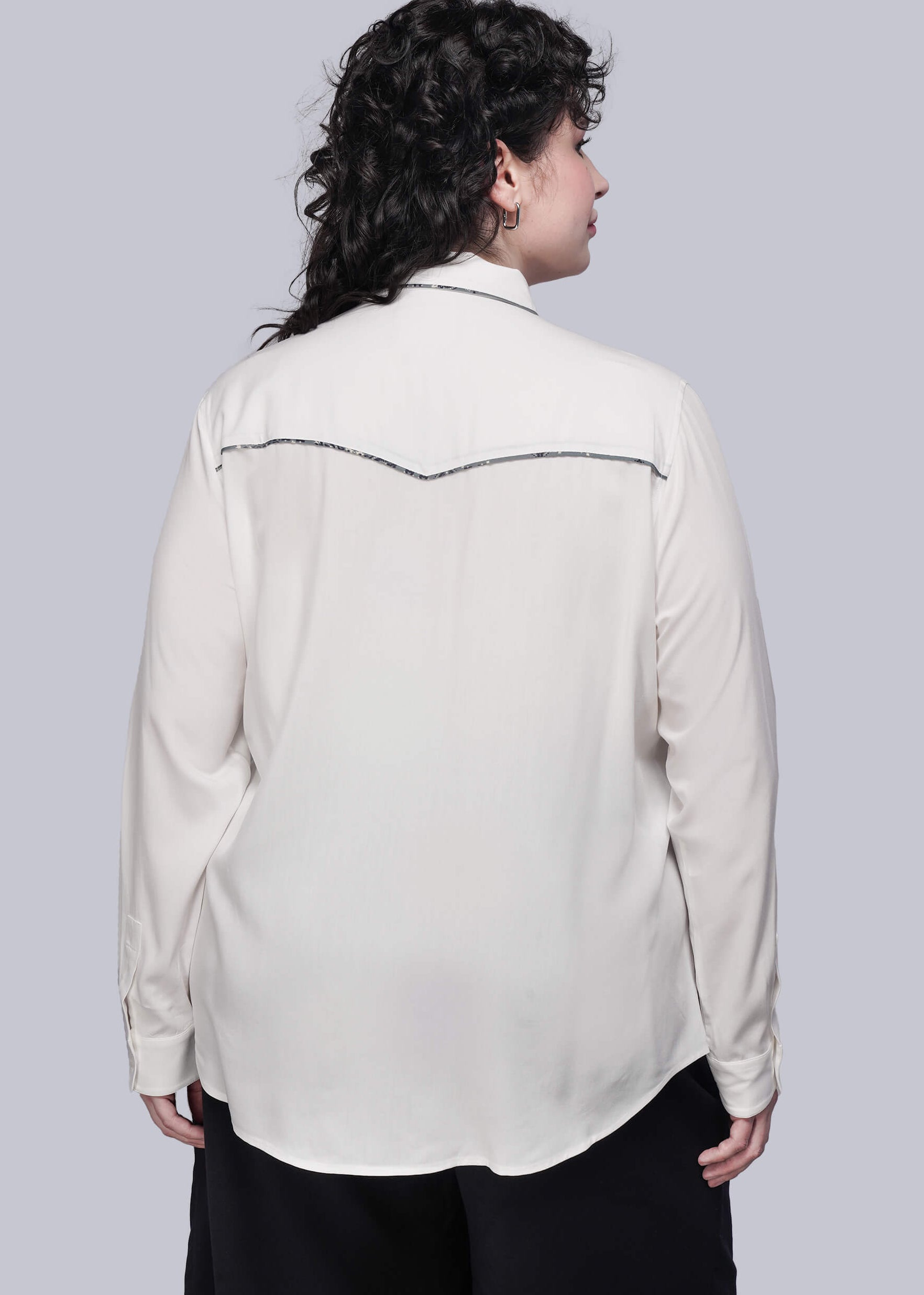 1X=Person wearing a white button up shirt with trim accents on a gray background