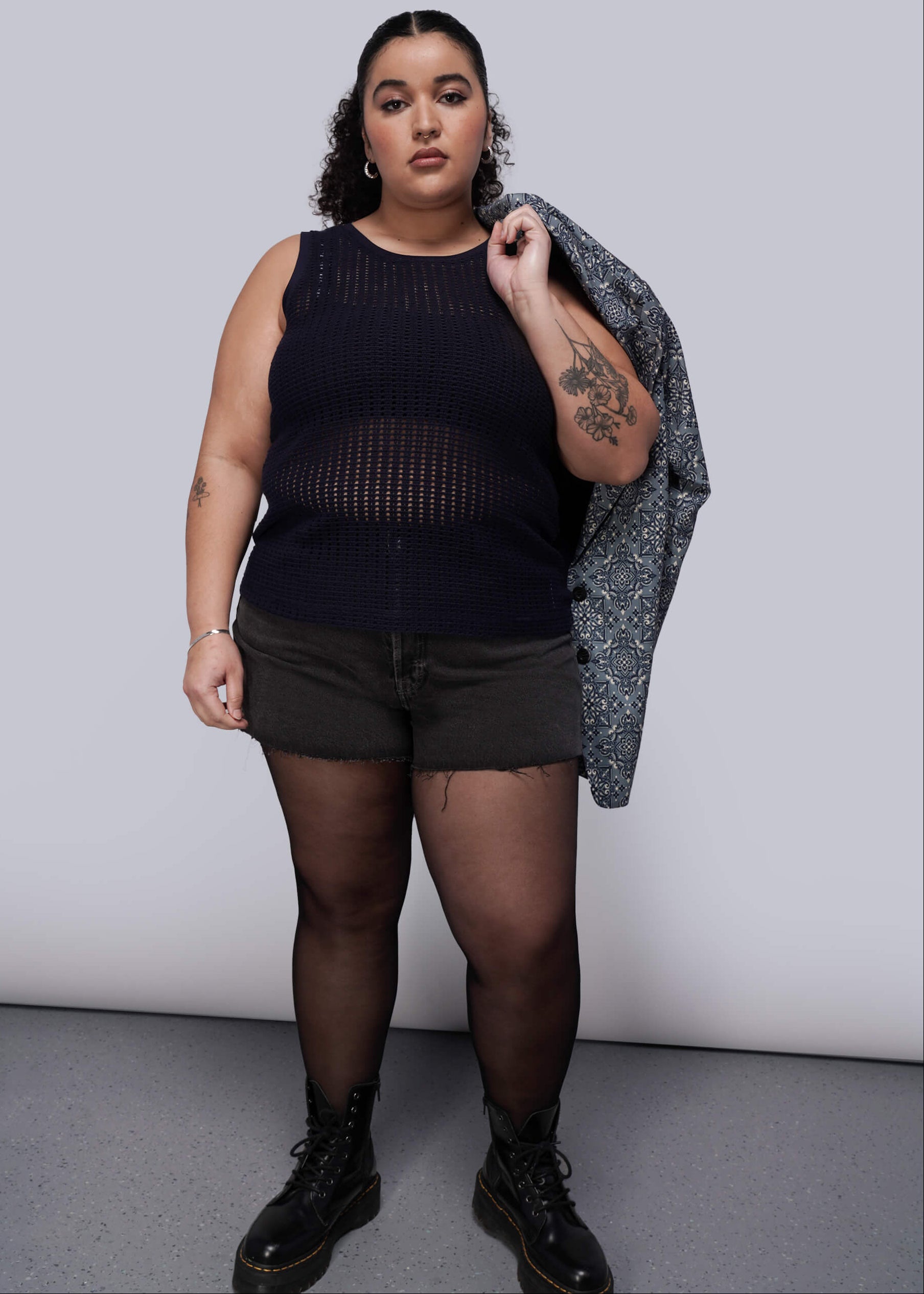 1X=Person wearing a navy blue knit mesh sleeveless top, black shorts, and black boots against a plain background