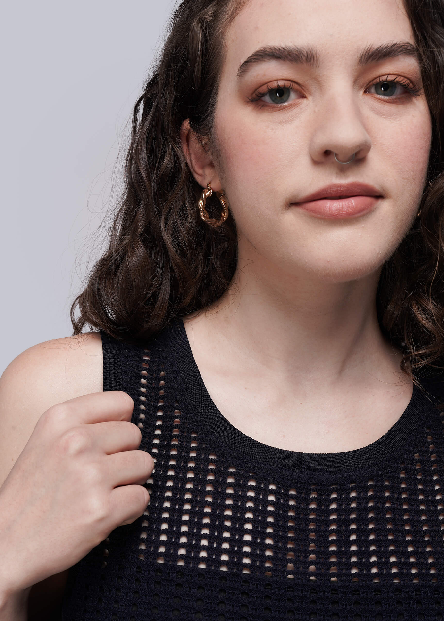 Woman wearing a navy blue knit mesh sleeveless top against a plain background