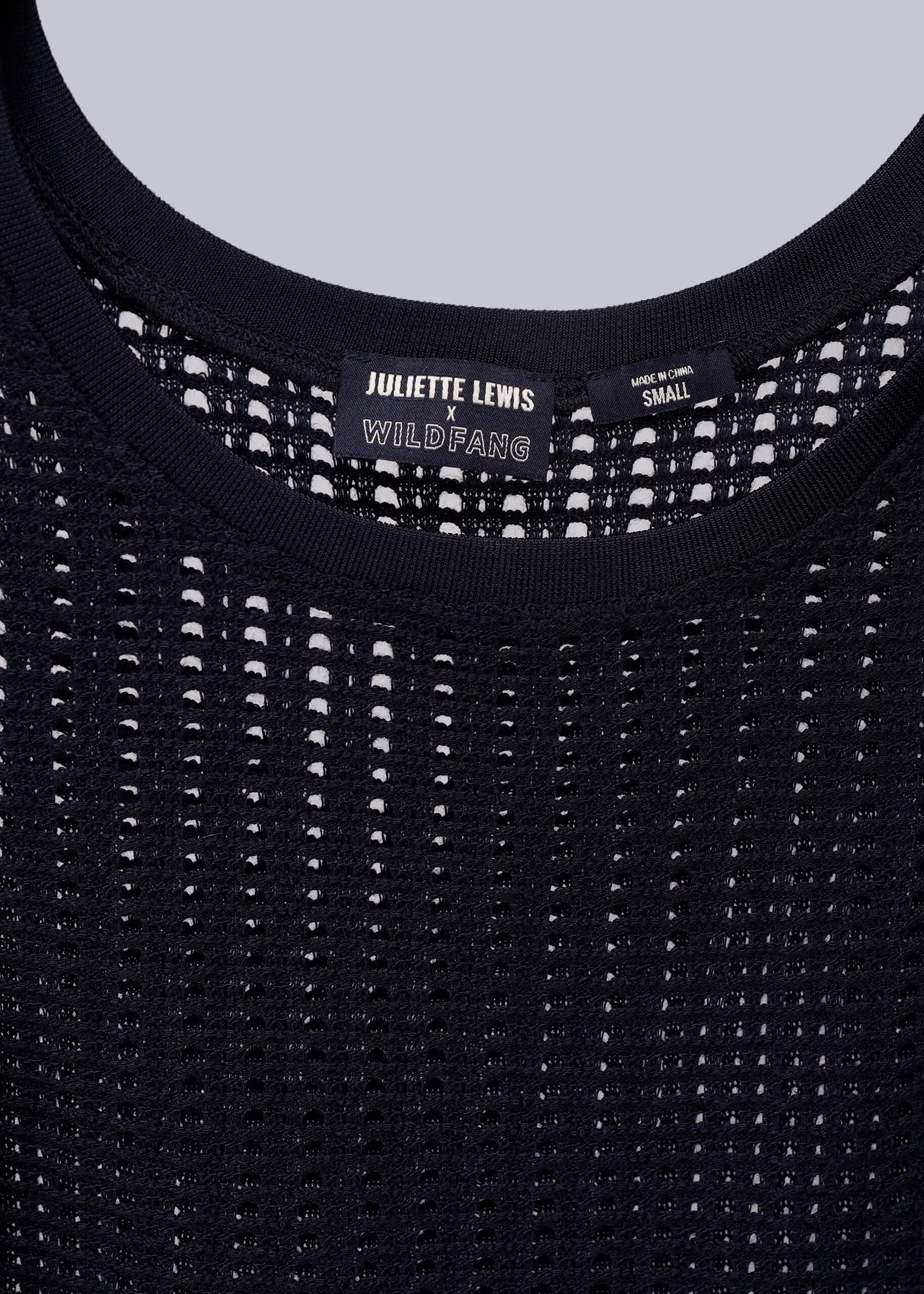 Close up of navy blue mesh tank top with 'Juliette Lewis x Wildfang' label on a light gray background