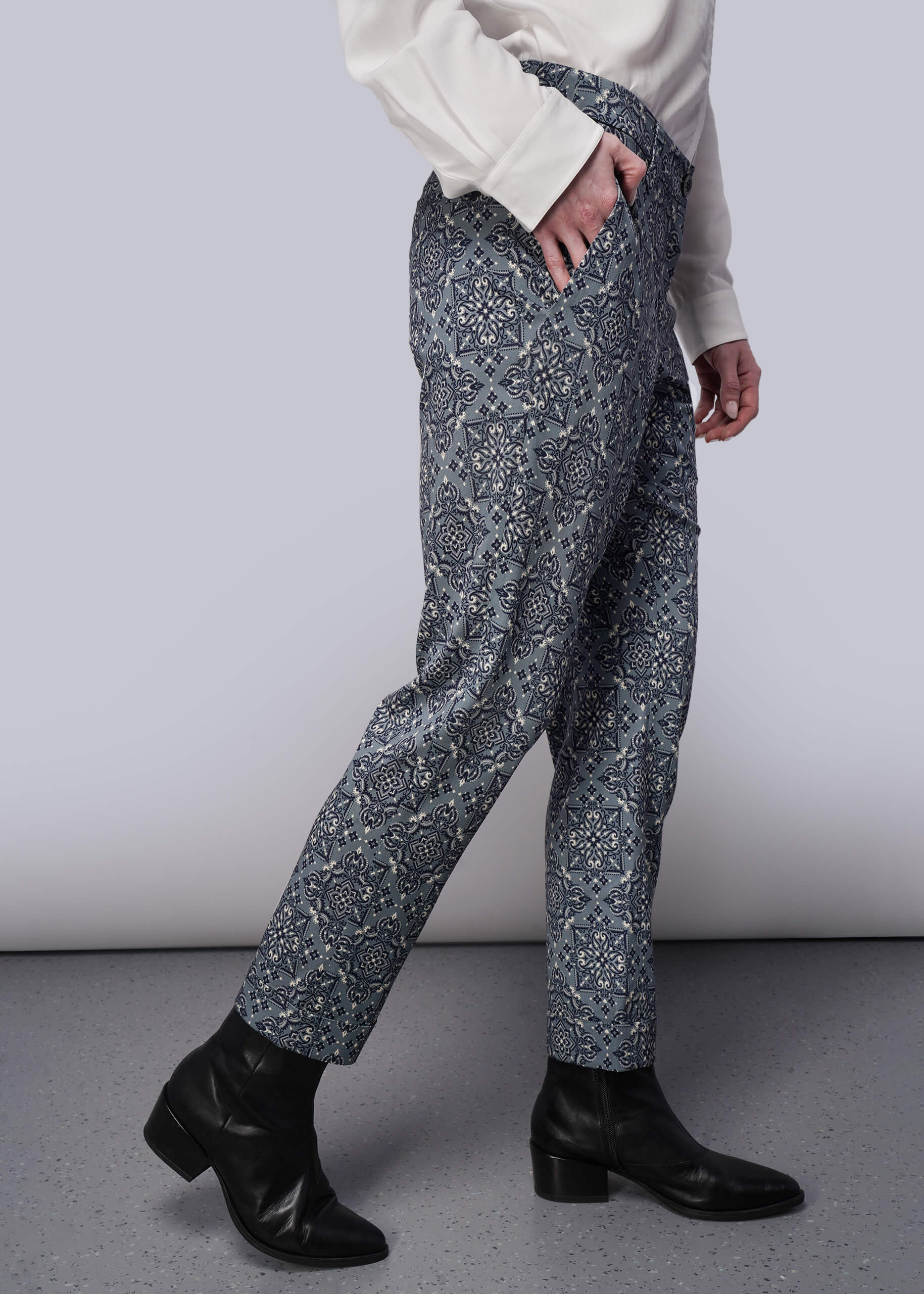 S=Person wearing patterned pants and black boots on a plain background