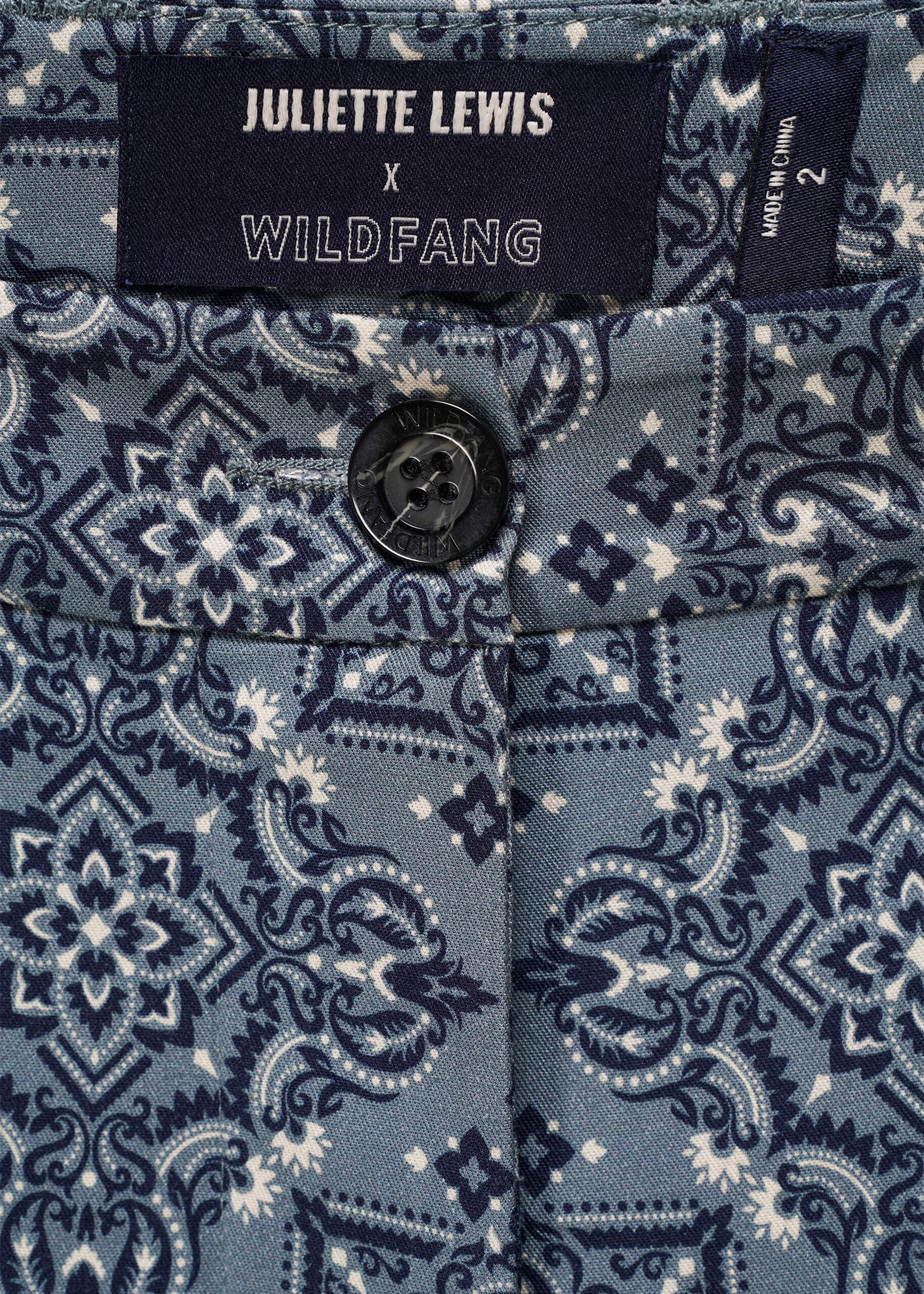 Close-up of a patterned trouser waistband with a brand label for Juliette Lewis x Wildfang.
