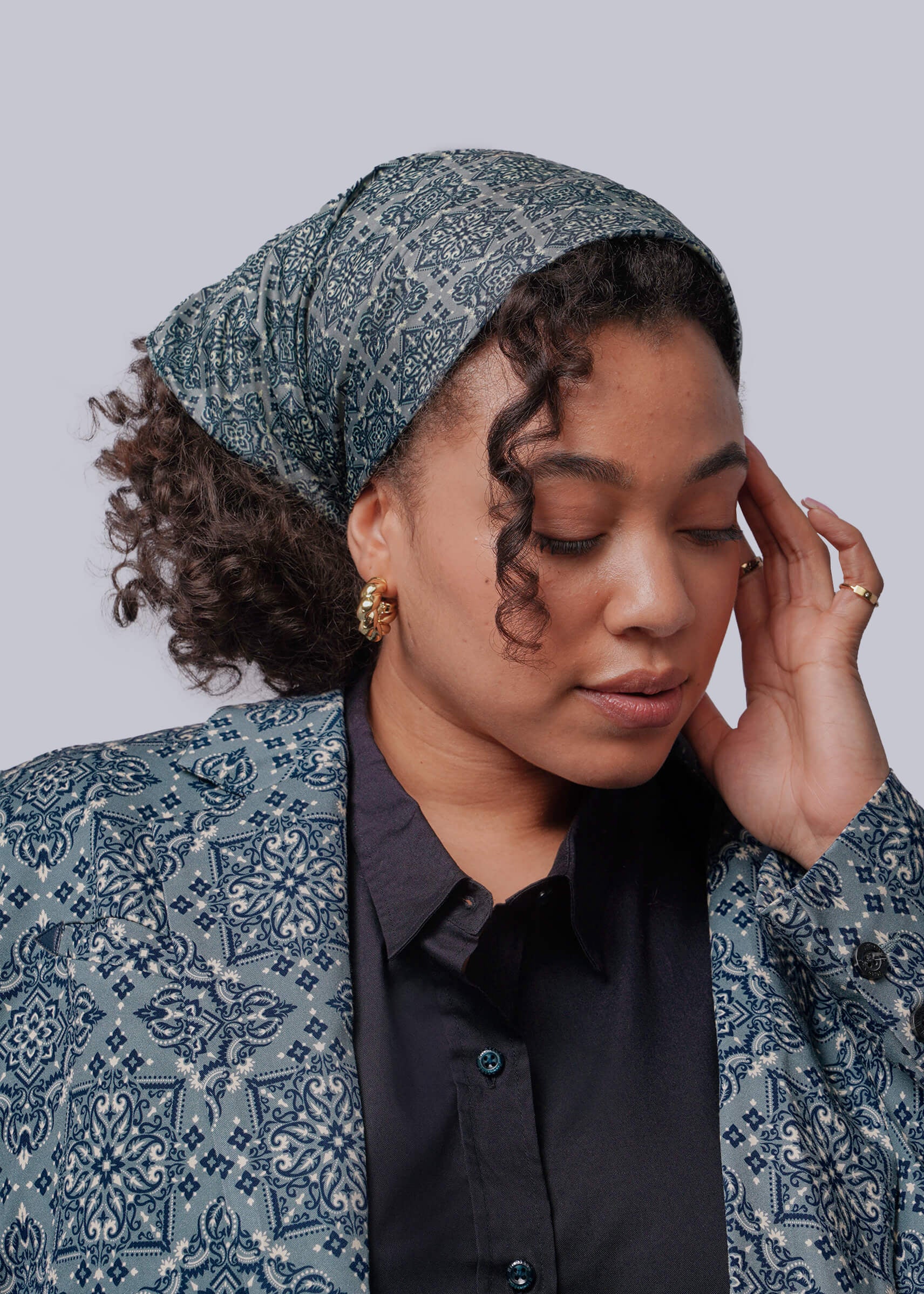 Woman wearing a patterned headscarf and jacket against a plain background