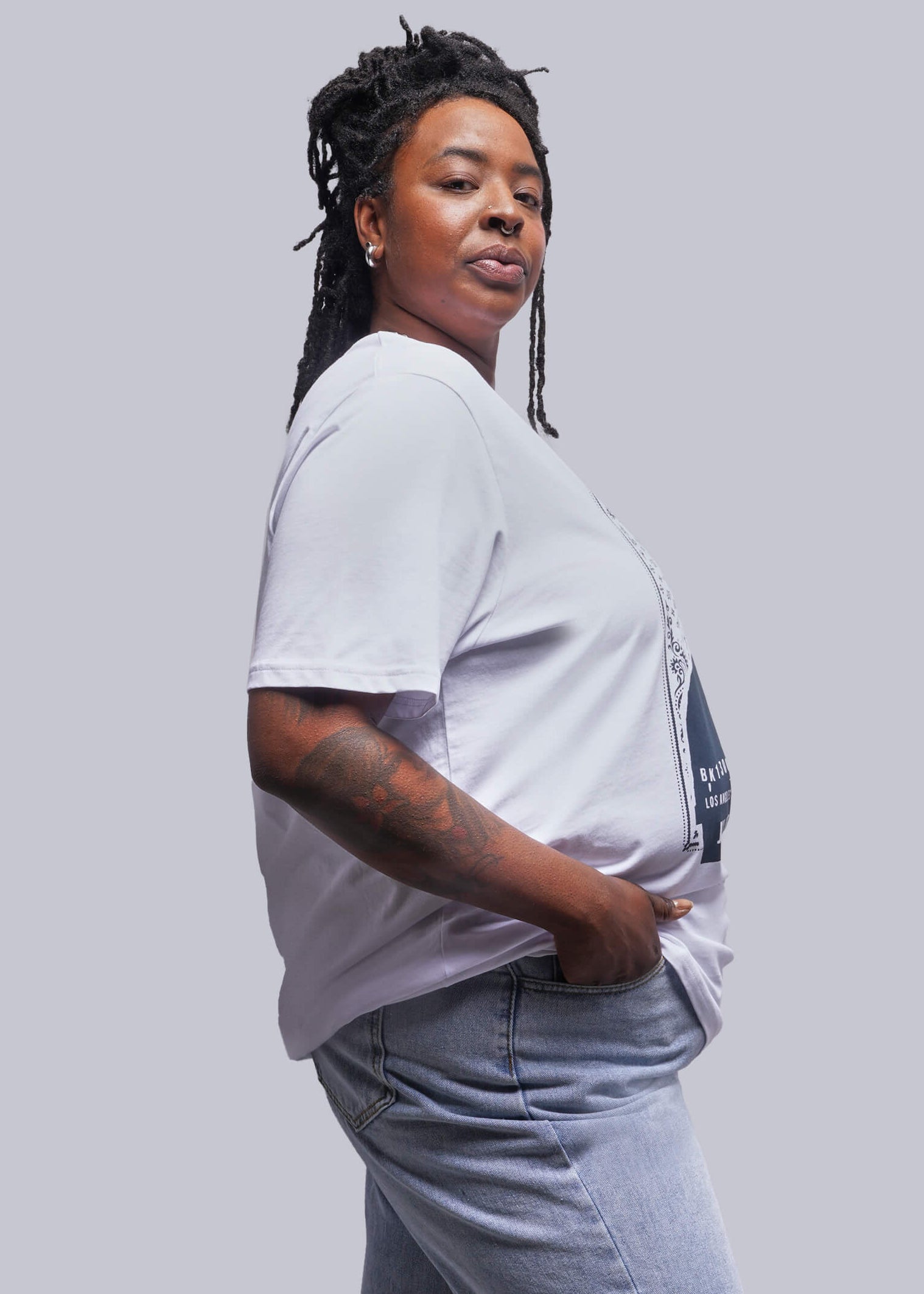 1X=Person wearing a white t-shirt and blue jeans against a plain background