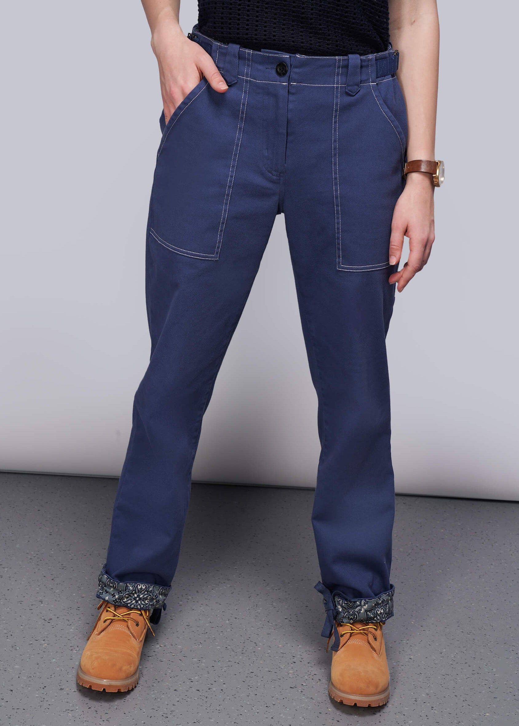 Person wearing blue pants and brown boots on a plain background