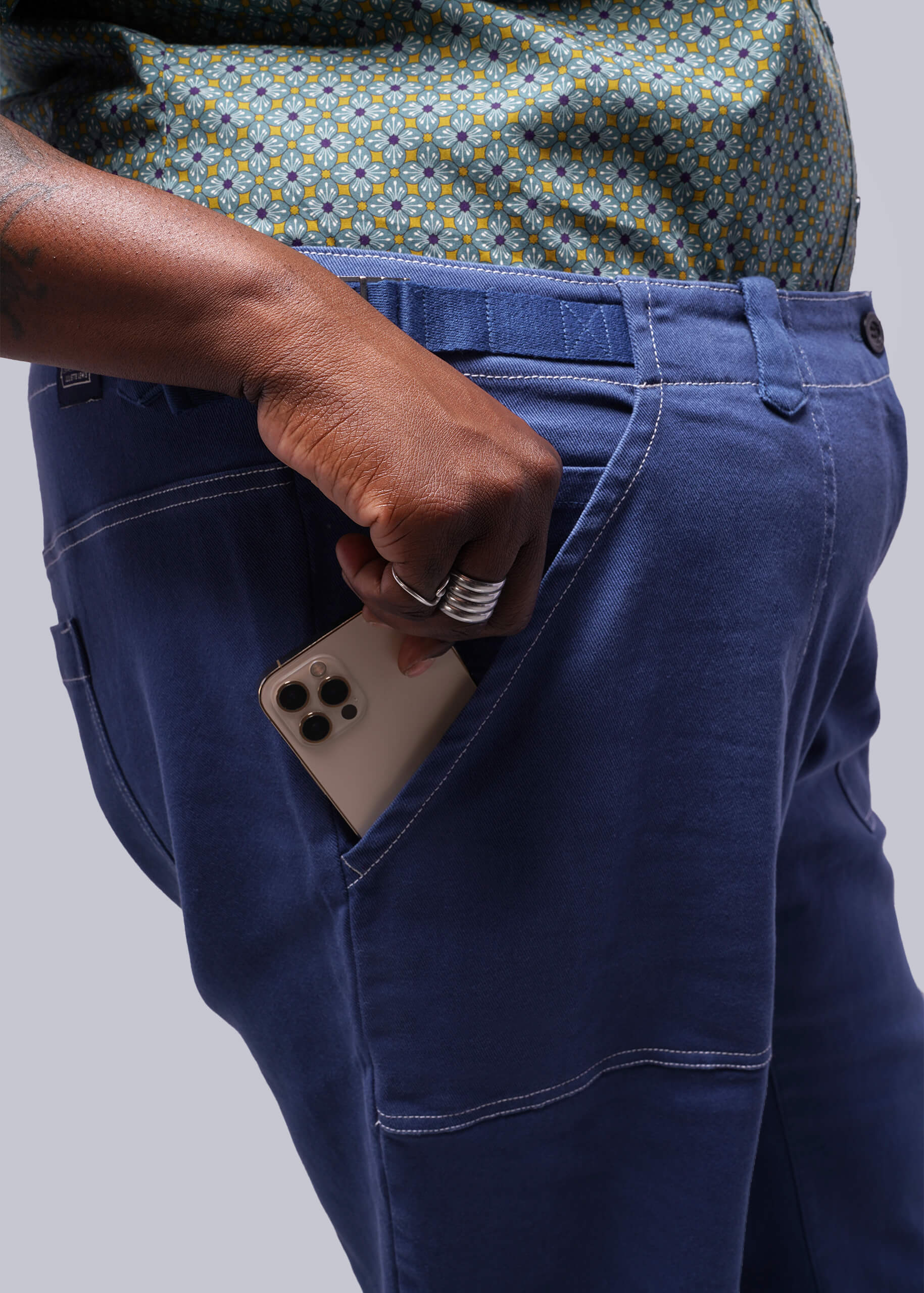 1X=Person wearing blue pants with a phone in the pocket against a plain background
