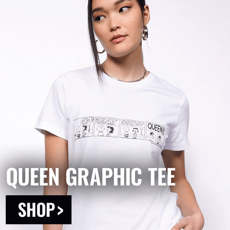 Person modeling the PEANUTS X WILDFANG Queen Graphic Tee with text overlay in bottom left corner that reads QUEEN GRAPHIC TEE and button that reads SHOP.
