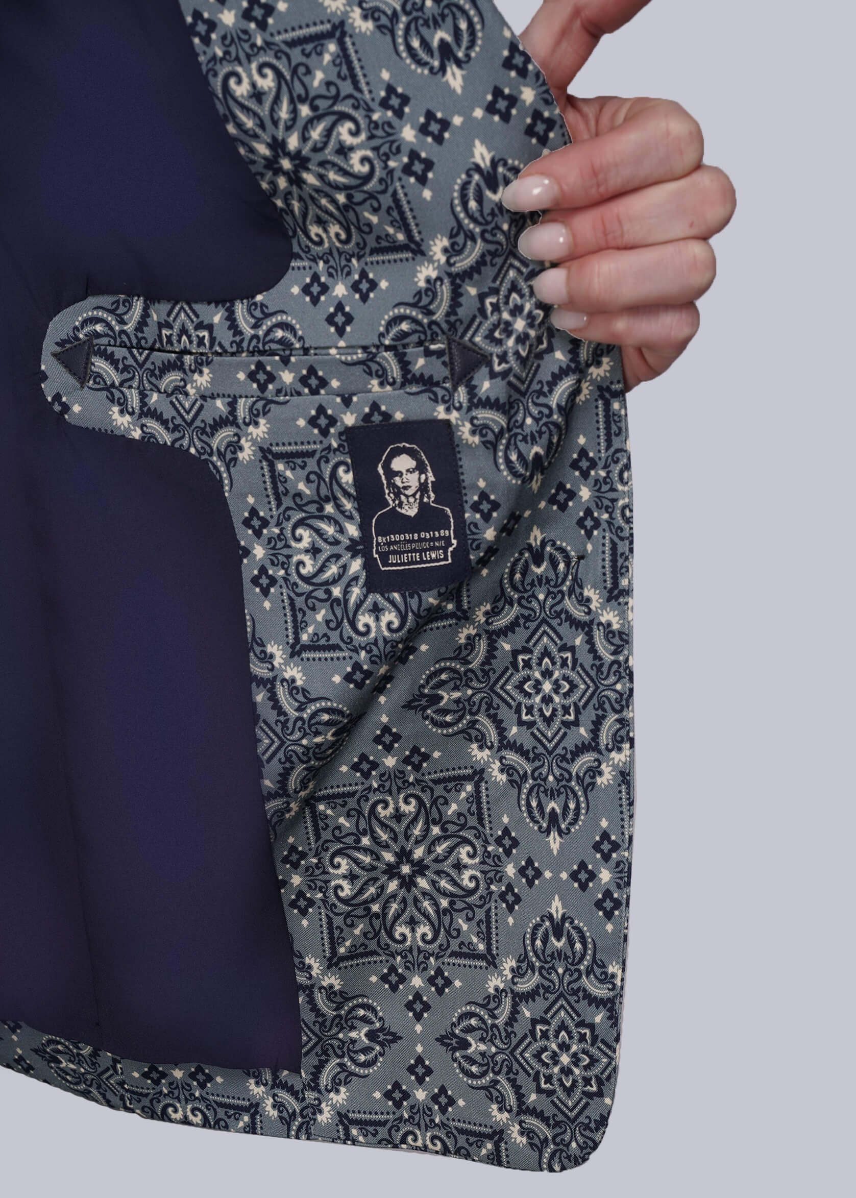 S=Hand holding a patterned blazer open with a visible brand label against a plain background