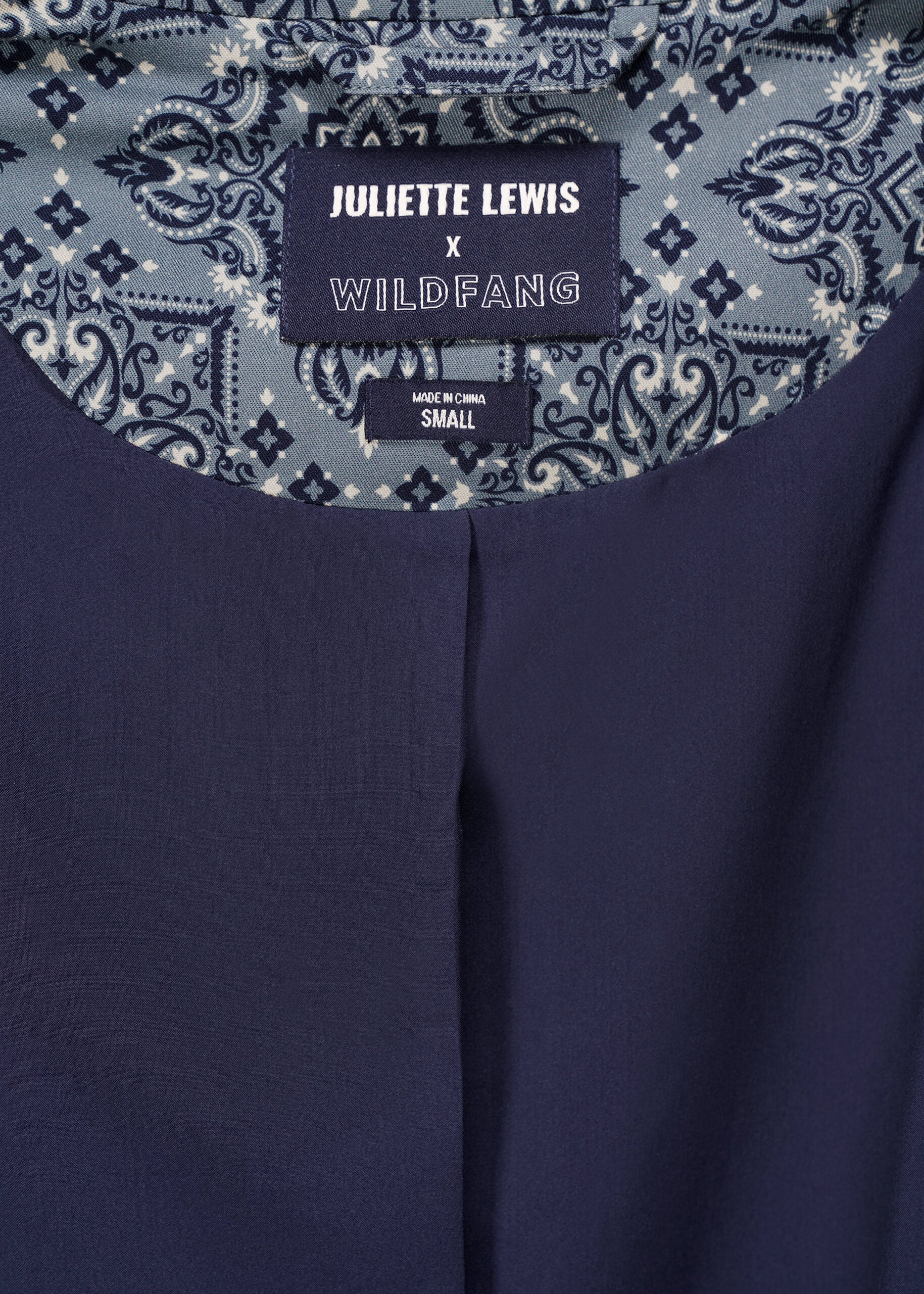 Image showing interior of blazer with 'Juliette Lewis x Wildfang' label on patterned teal fabric.