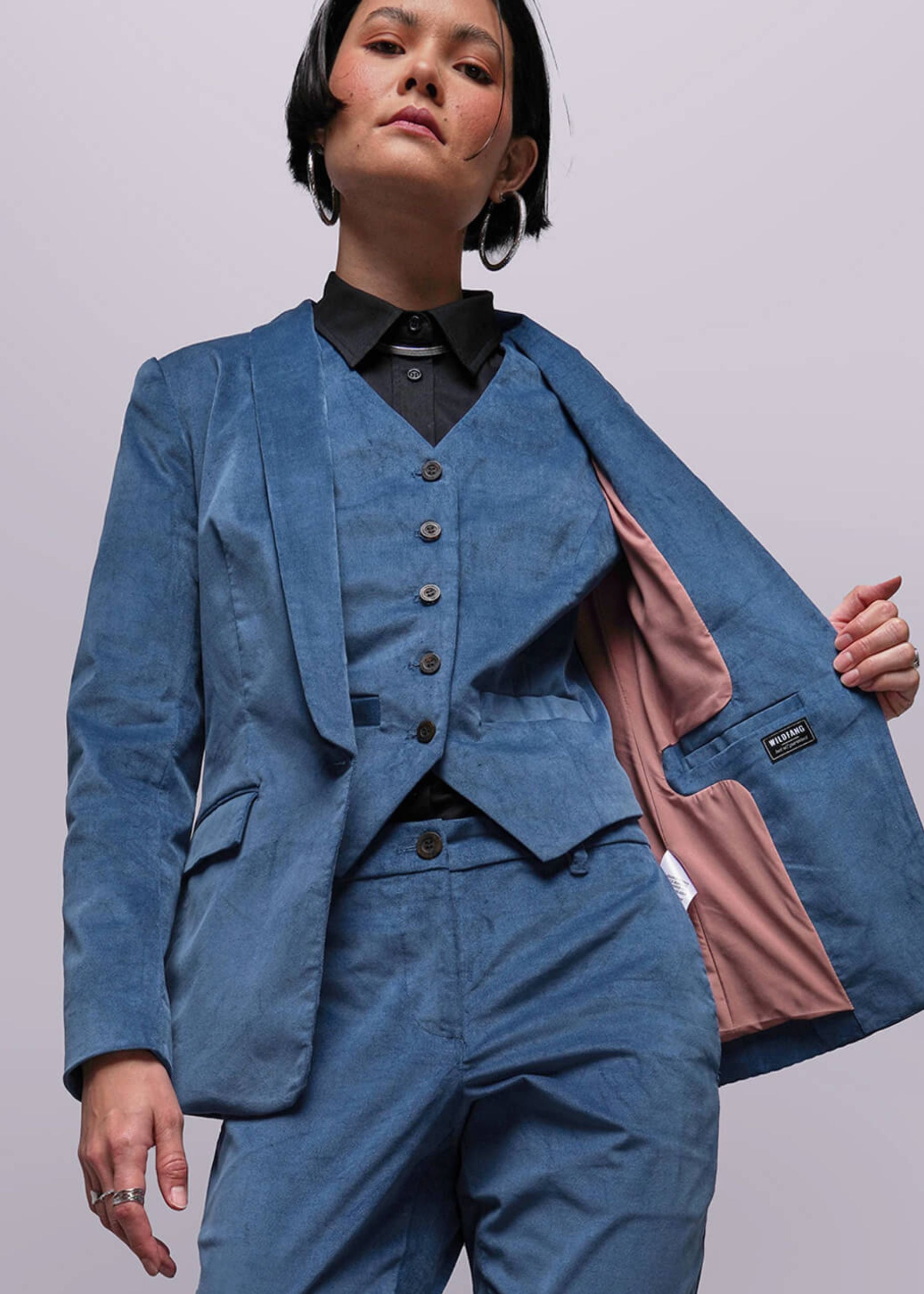 Person wearing a blue suit with a pink lining on a plain background