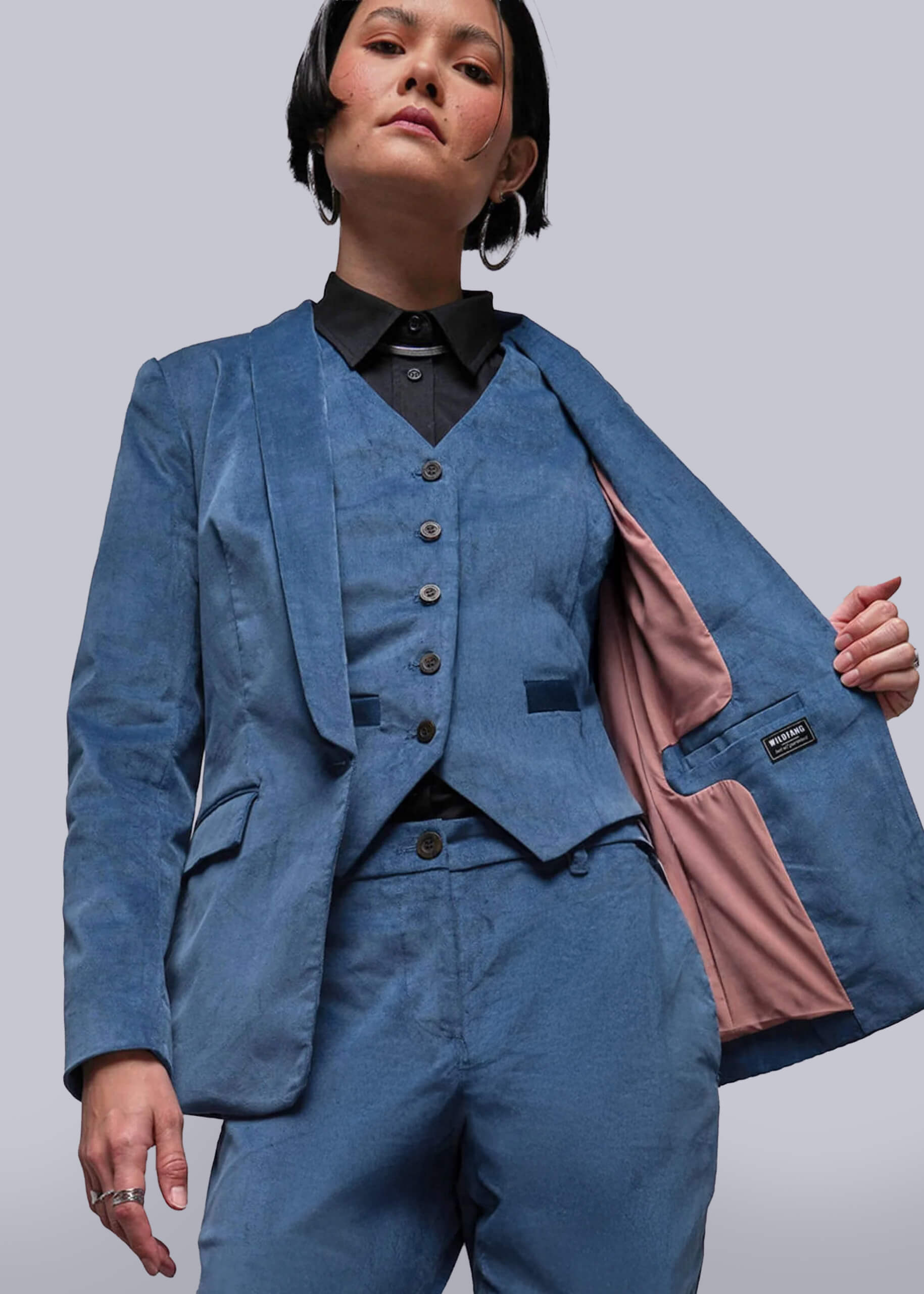 Person wearing a blue suit with a pink lining on a plain background