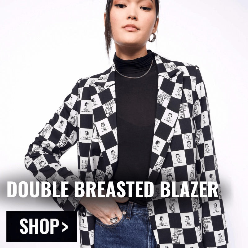 Close up of person modeling the Peanuts x Wildfang Double Breasted Blazer in a black and white checkered print. Text overlay on bottom left corner reads Double Breasted Blazer and button underneath reads SHOP.