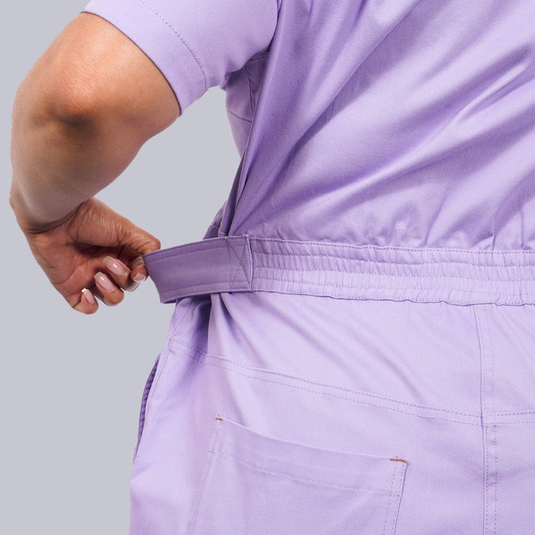 Close up of waistband on purple coverall with hand pulling waistband to show stretch