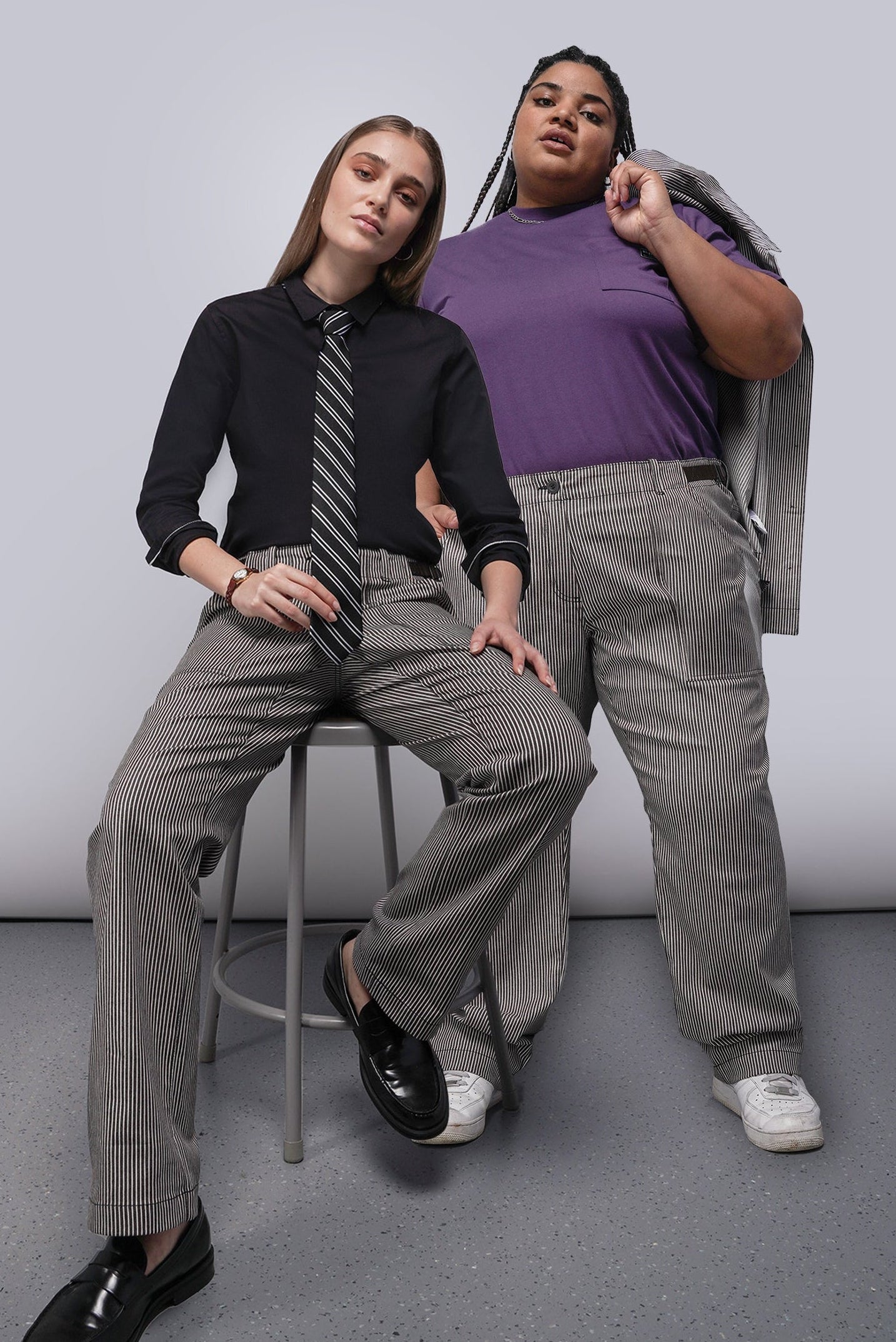 Two people wearing brown and white striped pants against a plain background