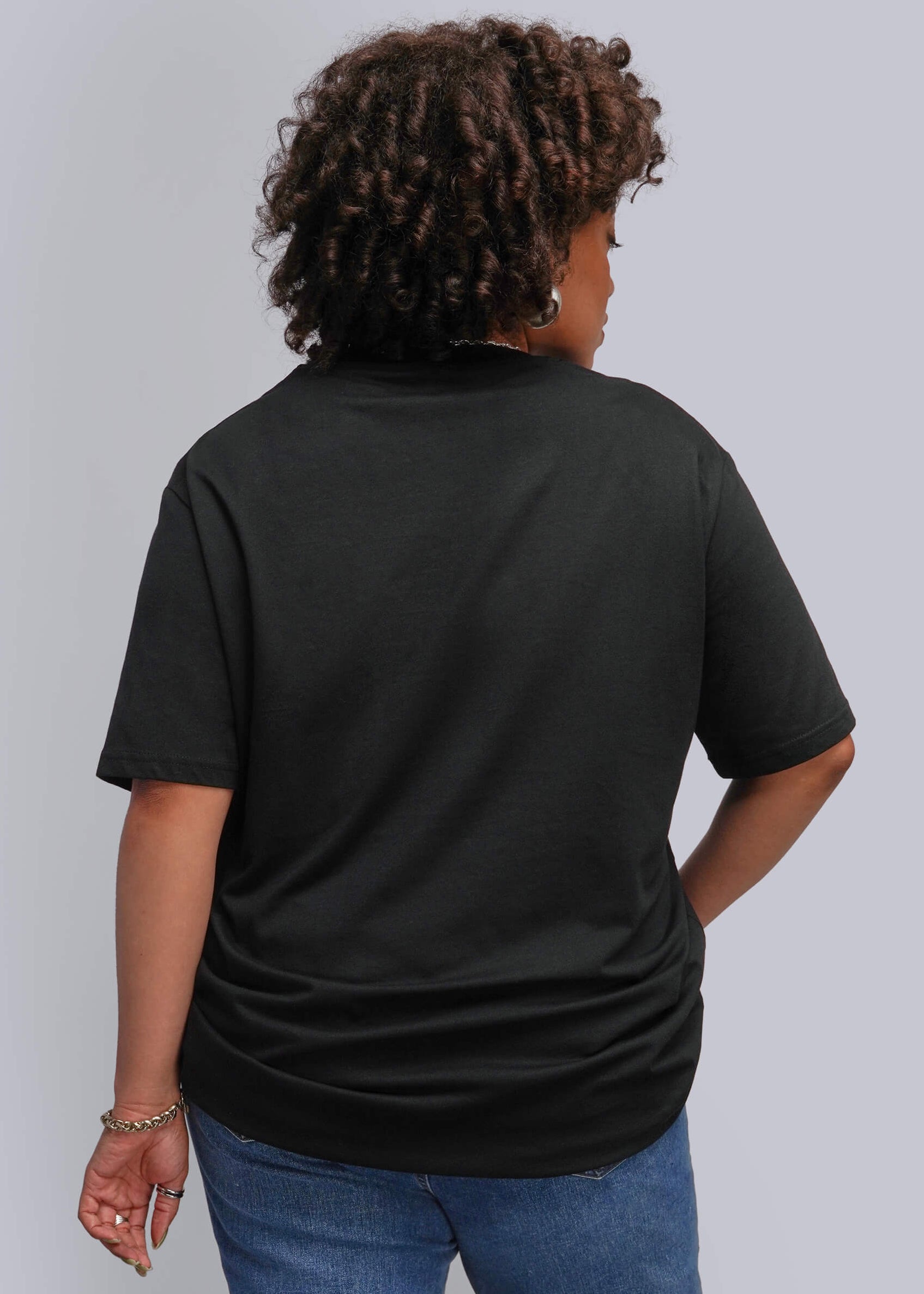 1X=A person shown from the back wearing a black short-sleeve t-shirt and blue jeans against a light gray studio background.