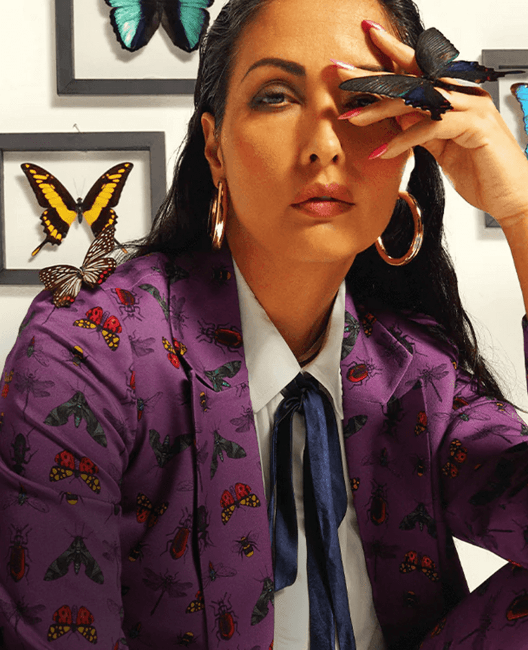 Woman wearing a purple jacket with butterfly patterns in an indoor setting.