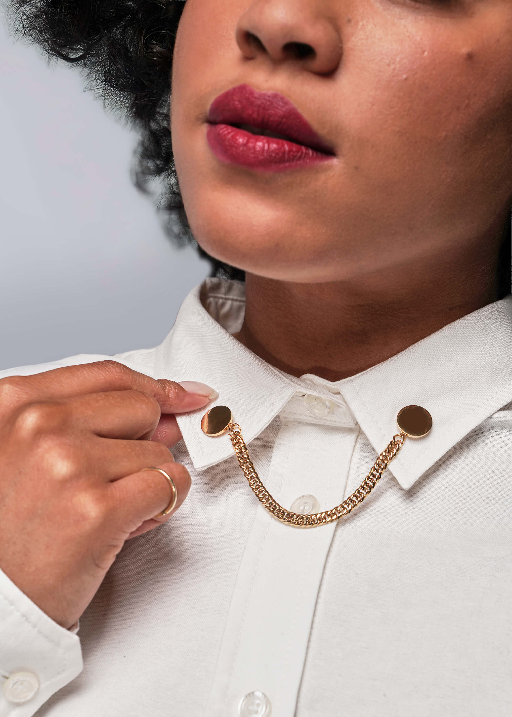 Person wearing a white shirt with gold chain collar accents